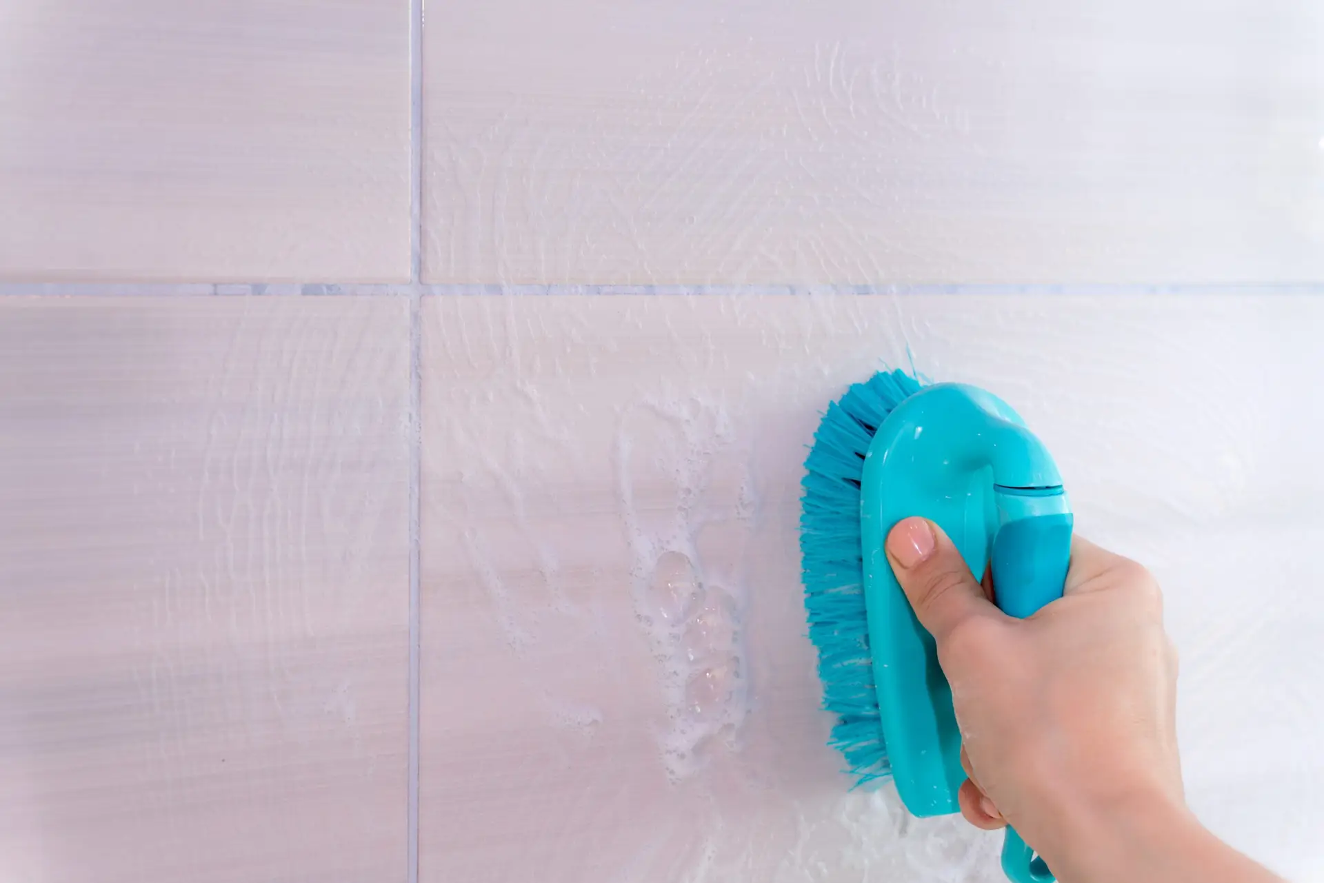 An Urgent Pro bond cleaning provider in Brisbane scrubbing the toilet, polishing the vanity mirror and cleaning tile grout in a Brisbane rental bathroom, with professional equipment visible in a realistic local service setting