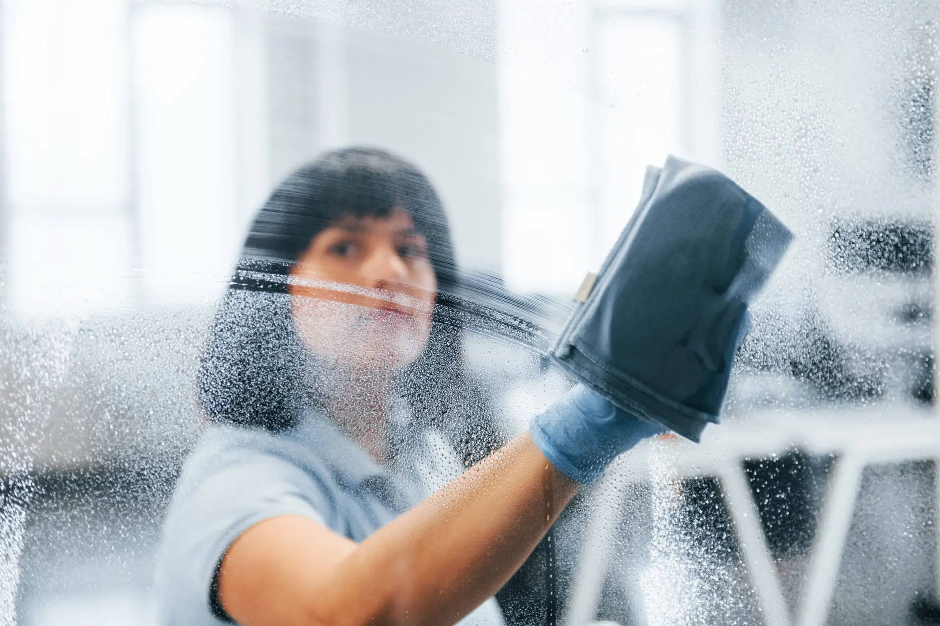 An Urgent Pro bond cleaning provider in Brisbane cleaning the glass and tracks of louvre windows and sliding doors in a Brisbane rental ahead of final inspection, with professional equipment visible in a realistic local service setting