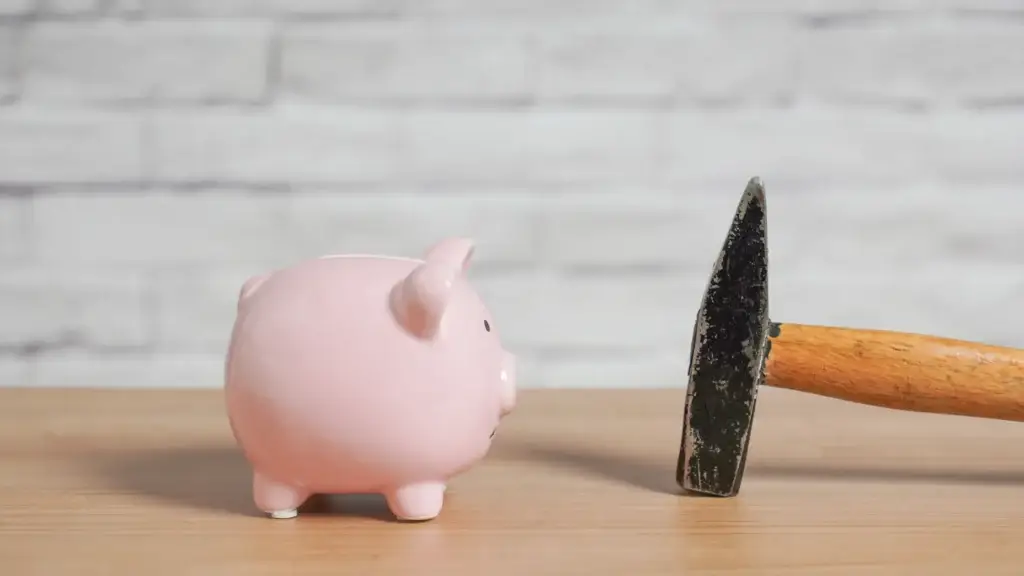 Pink piggy bank next to a hammer on a wooden table representing bond money at risk from repair costs