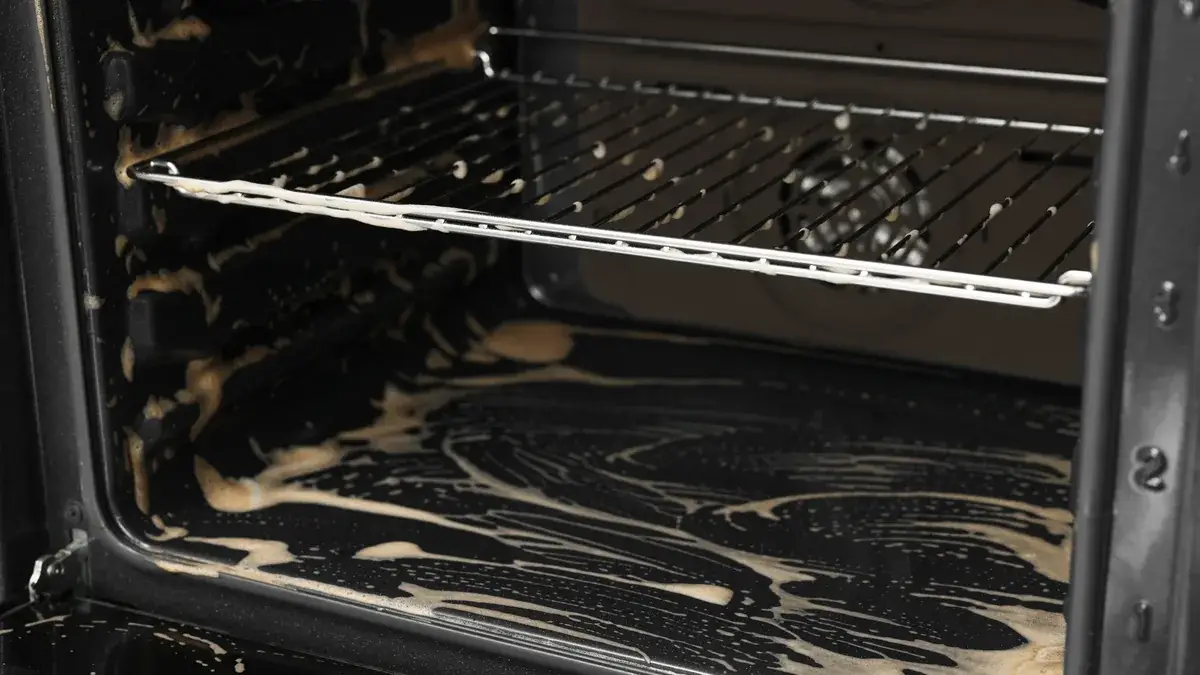 Heavily soiled oven interior with burnt-on grease and baked residue coating the floor and side walls