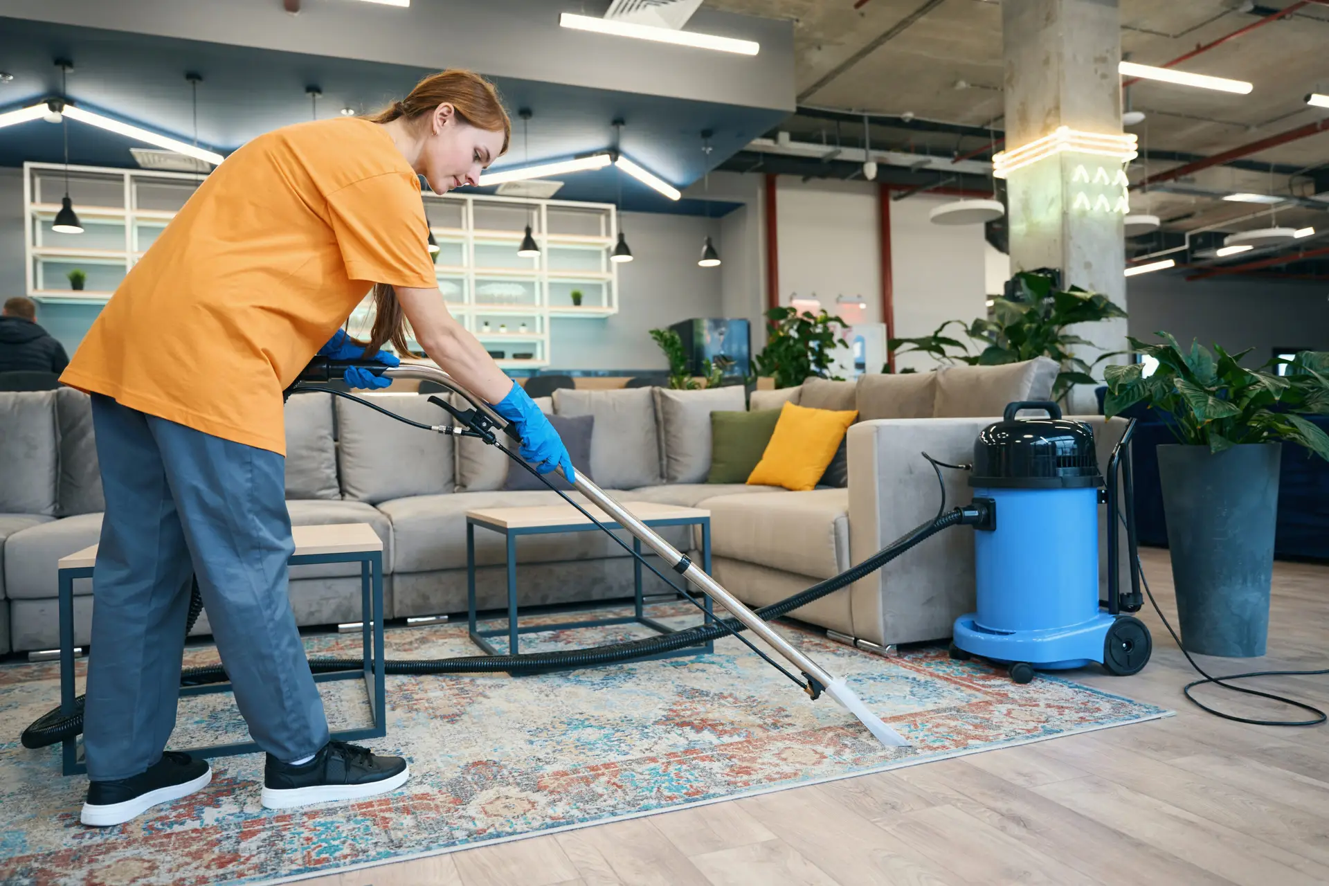 An Urgent Pro carpet cleaning provider in Gold Coast working methodically in rows across a large carpeted living area, with professional equipment visible in a realistic local service setting