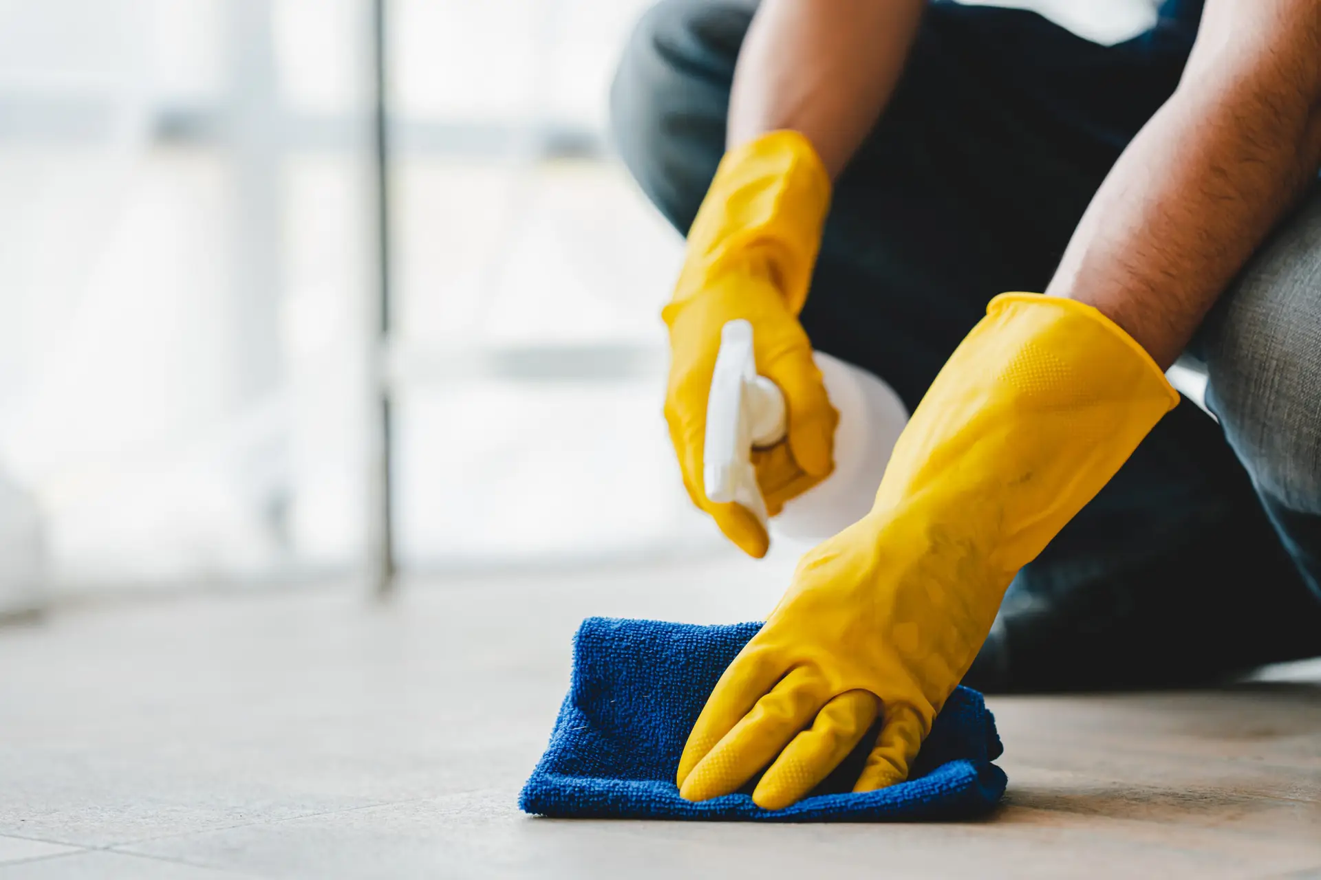 An Urgent Pro carpet cleaning provider in Gold Coast applying a pre-treatment spray to a visible carpet stain before steam cleaning, with professional equipment visible in a realistic local service setting