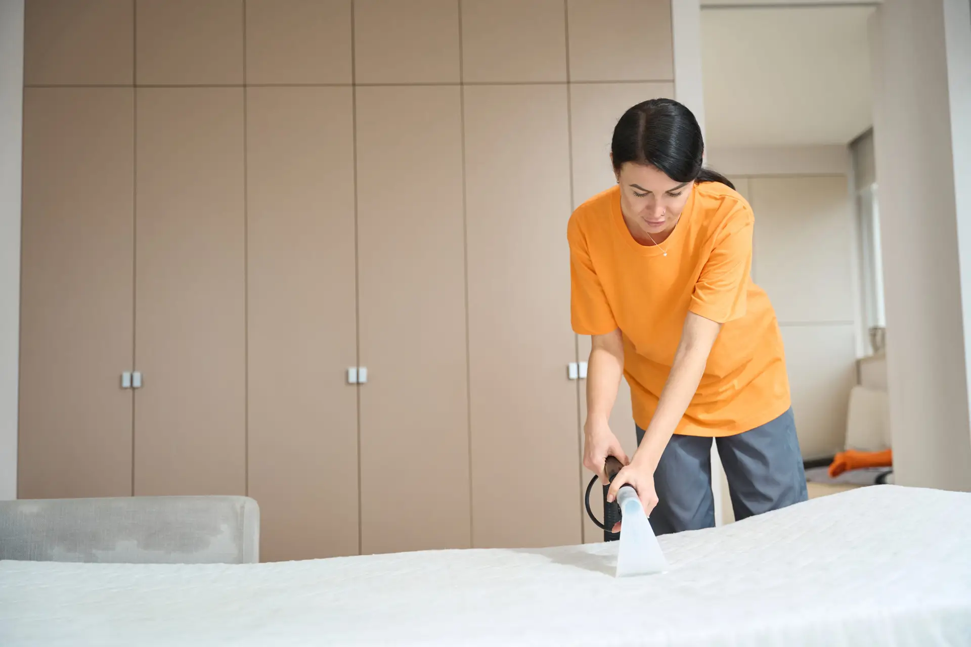 An Urgent Pro carpet cleaning provider in Sydney cleaning bedroom carpet edges and corners using a detail wand, with professional equipment visible in a realistic local service setting