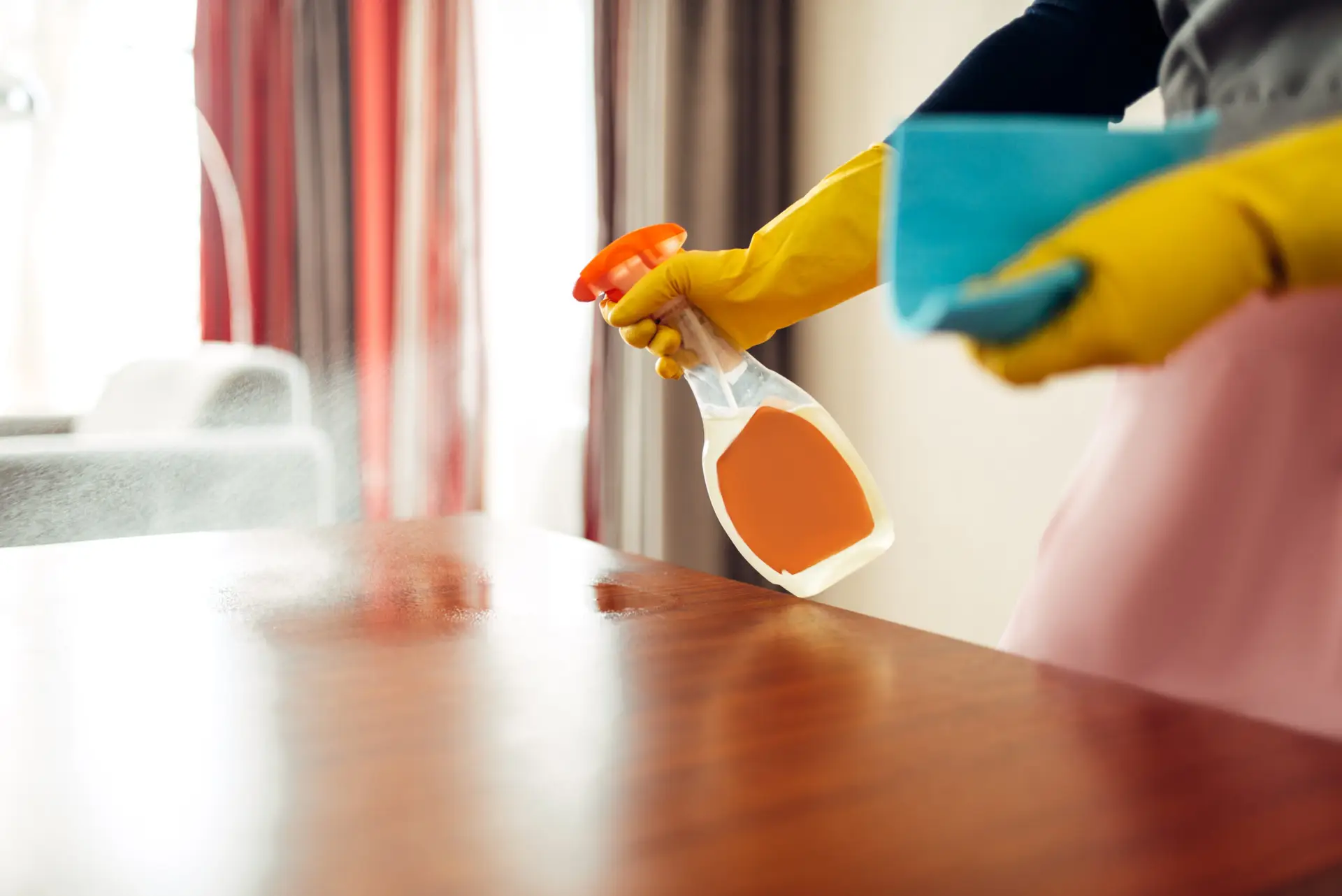 An Urgent Pro carpet cleaning provider in Sydney applying a pre-treatment spray to a visible carpet stain before steam cleaning, with professional equipment visible in a realistic local service setting