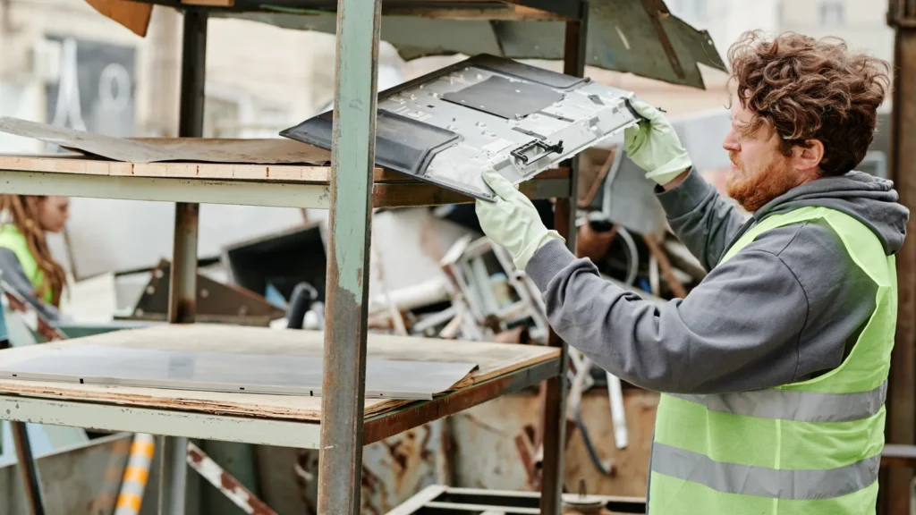 Technician sorting old monitors and computers at an e-waste recycling facility in Australia