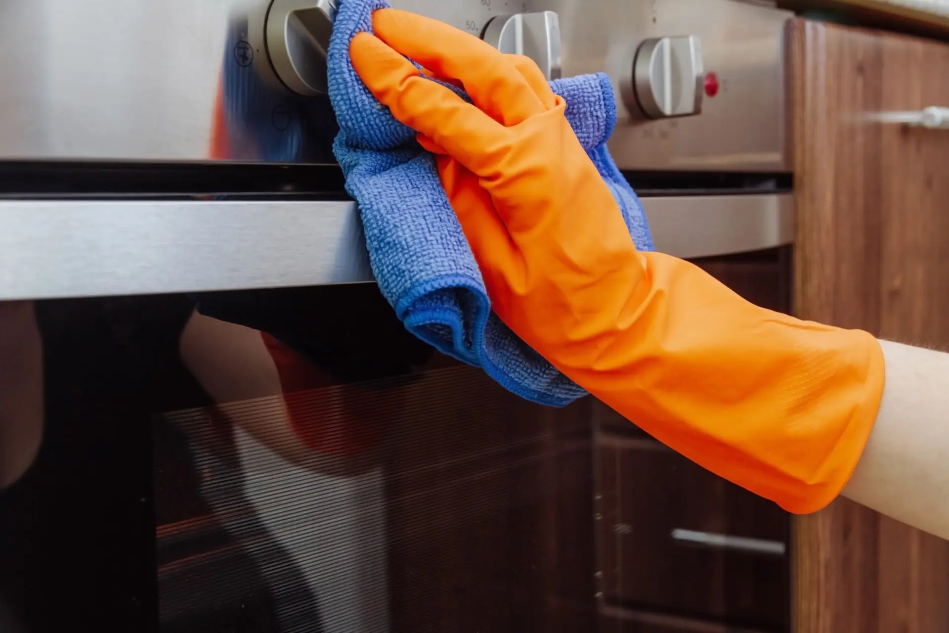 An Urgent Pro end of lease cleaning provider in Melbourne cleaning the inside of the oven and wiping the stovetop in a Melbourne rental kitchen before the property is returned, with professional equipment visible in a realistic local service setting