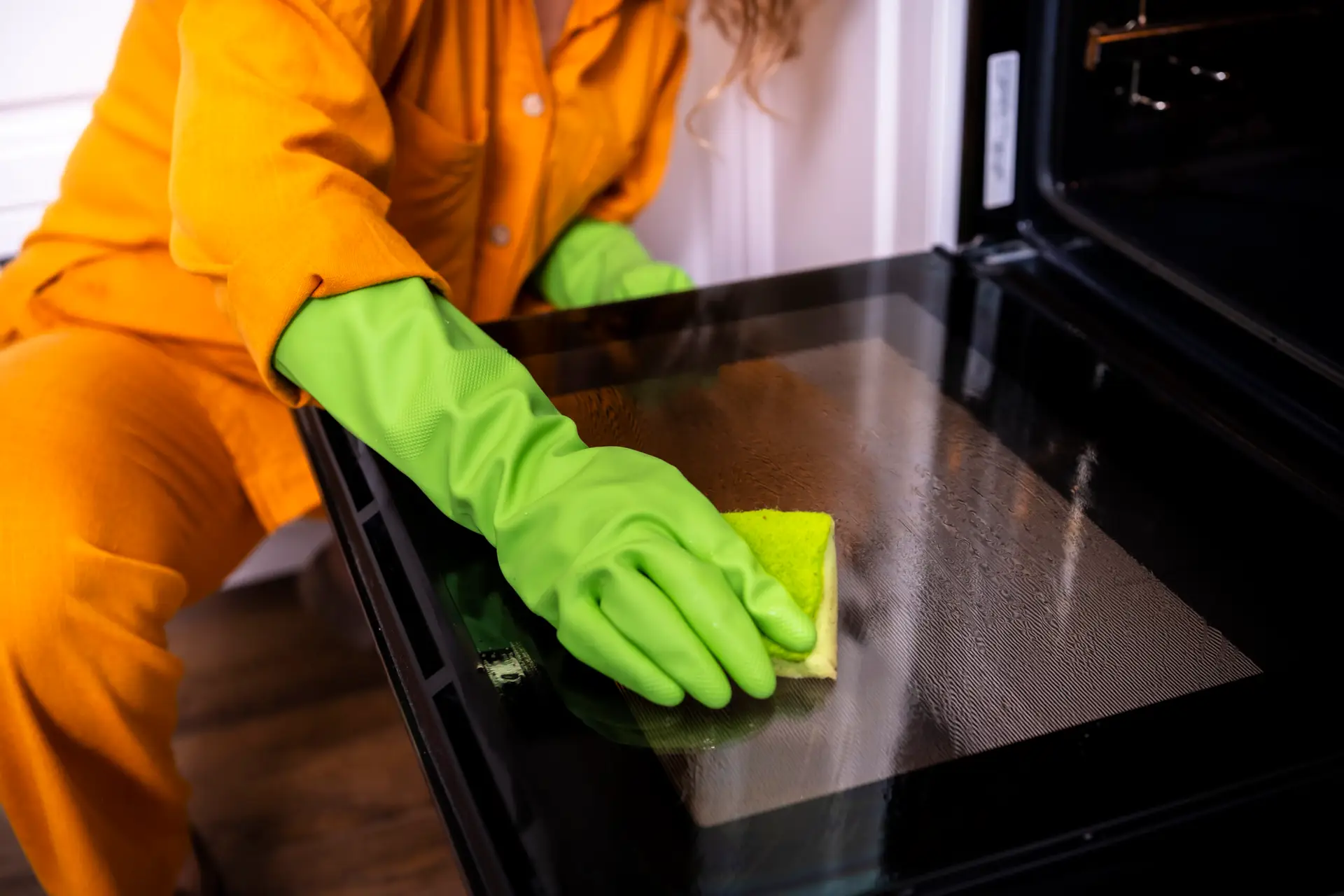An Urgent Pro end of lease cleaning provider in Perth cleaning the oven interior and wiping behind kitchen appliances in a Perth rental preparing for the end of lease inspection, with professional equipment visible in a realistic local service setting