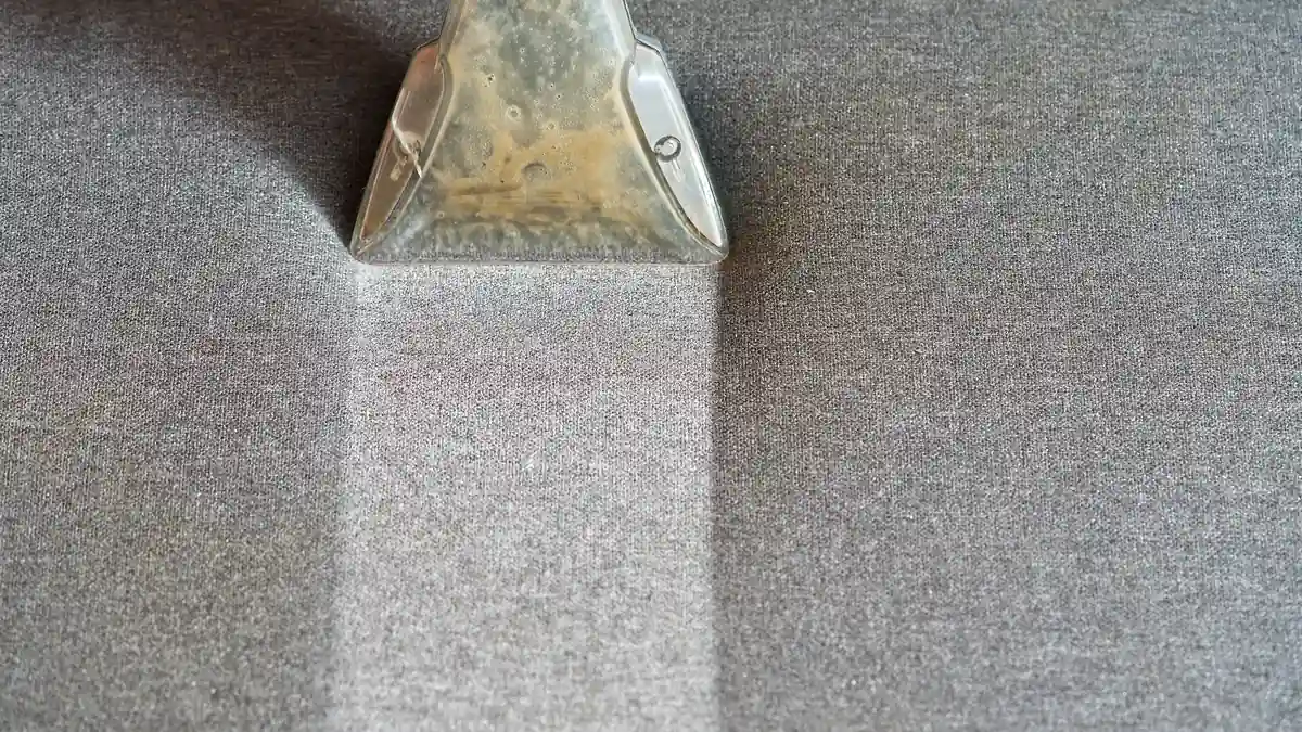 Portable extraction head drawing a clean line across grey woven fabric during a professional clean
