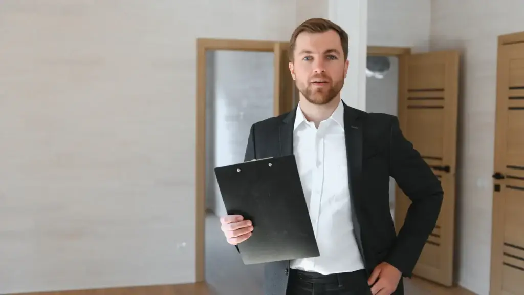 Property manager with clipboard standing in empty unfurnished rental property during end of lease inspection