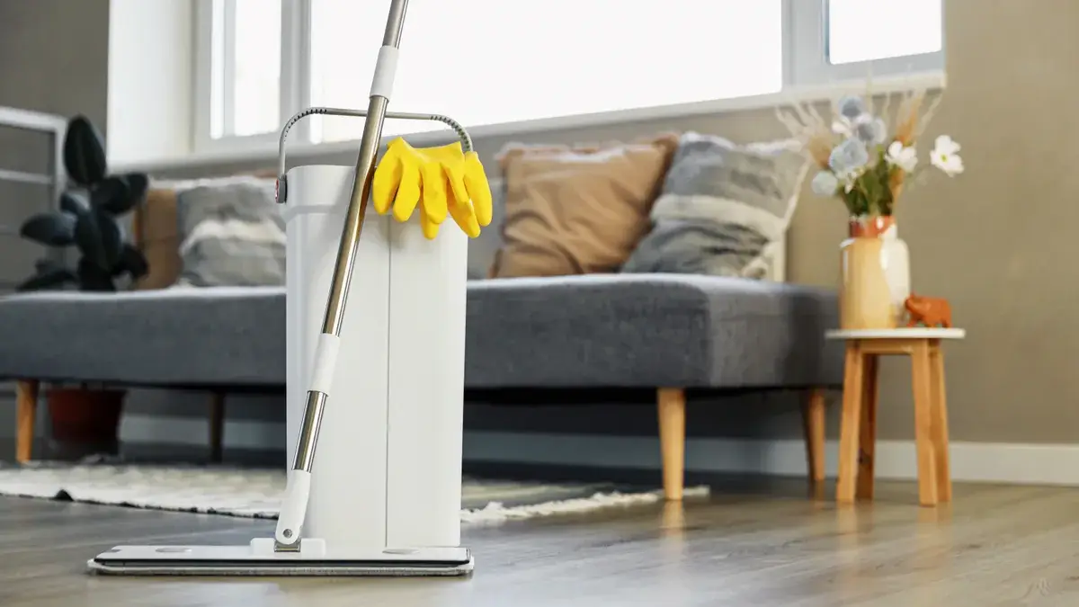 Flat mop and yellow rubber gloves resting in a lounge room ready for a professional house cleaning visit