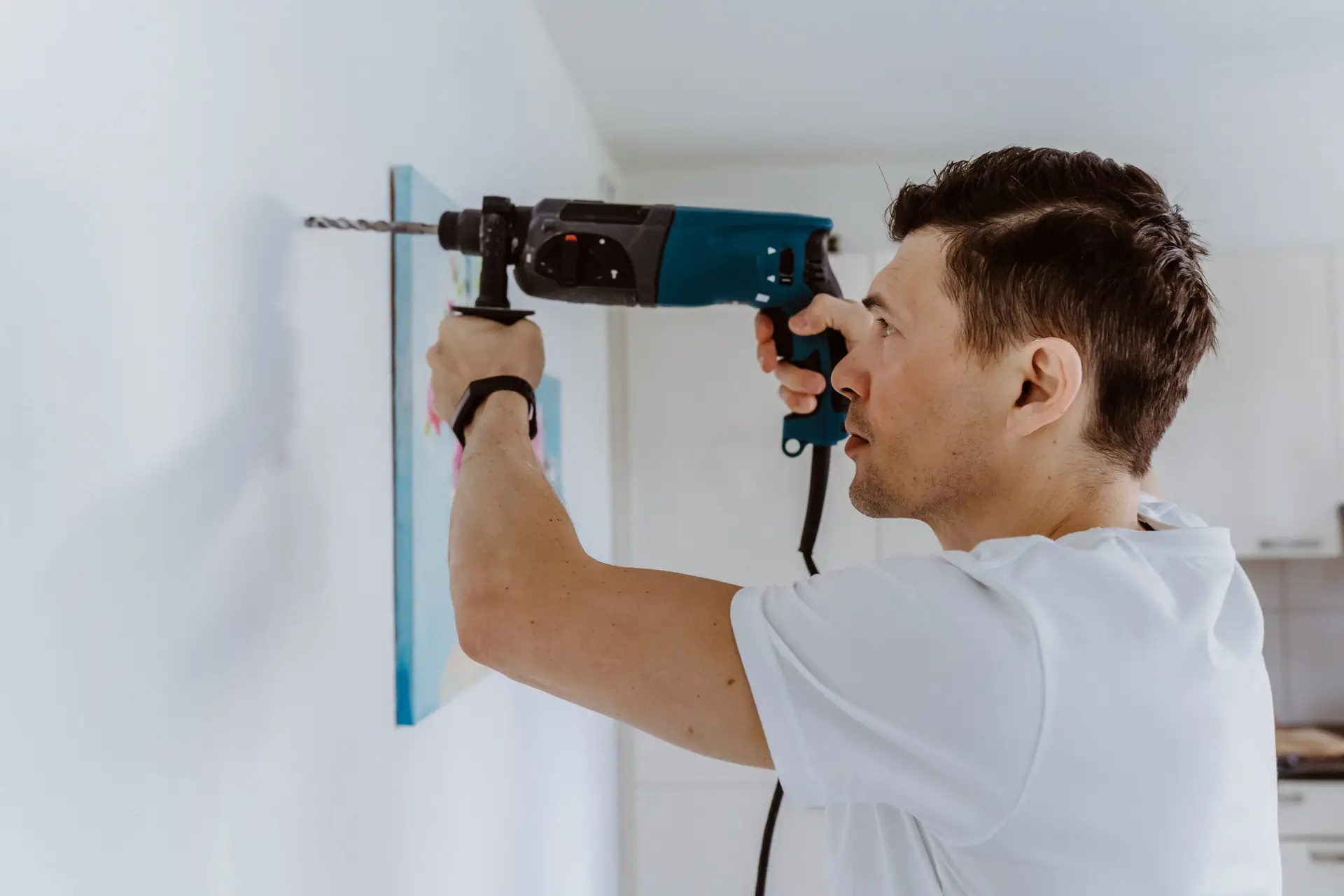 An Urgent Pro handyman provider in Brisbane drilling into a wall to mount a TV bracket using a stud finder and spirit level, with professional equipment visible in a realistic local service setting
