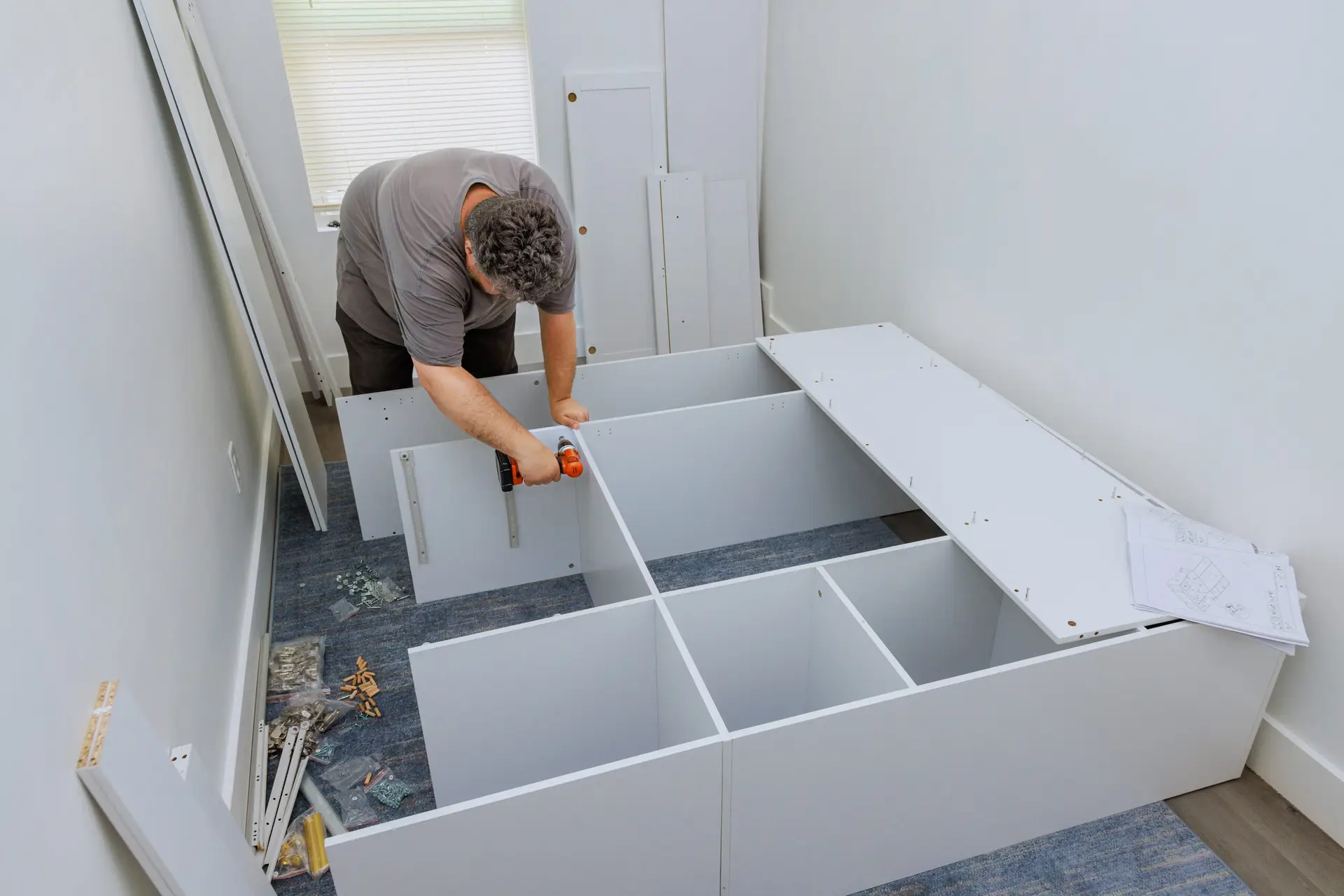 An Urgent Pro handyman provider in Brisbane assembling a flat-pack wardrobe following the instruction sheet with a mallet and Allen key, with professional equipment visible in a realistic local service setting