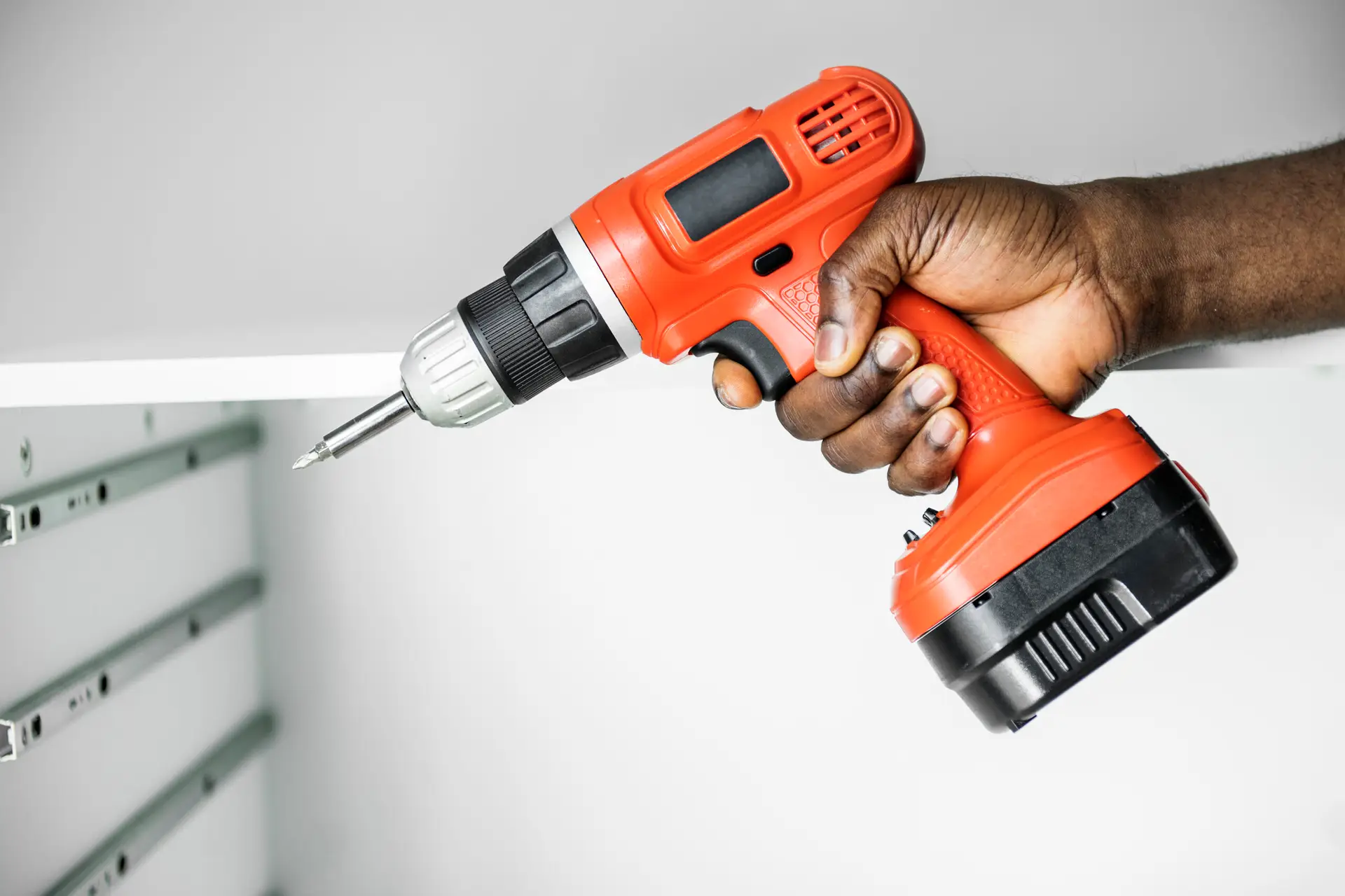 An Urgent Pro handyman provider in Brisbane measuring, drilling and installing floating wall shelves with a spirit level and wall anchors, with professional equipment visible in a realistic local service setting