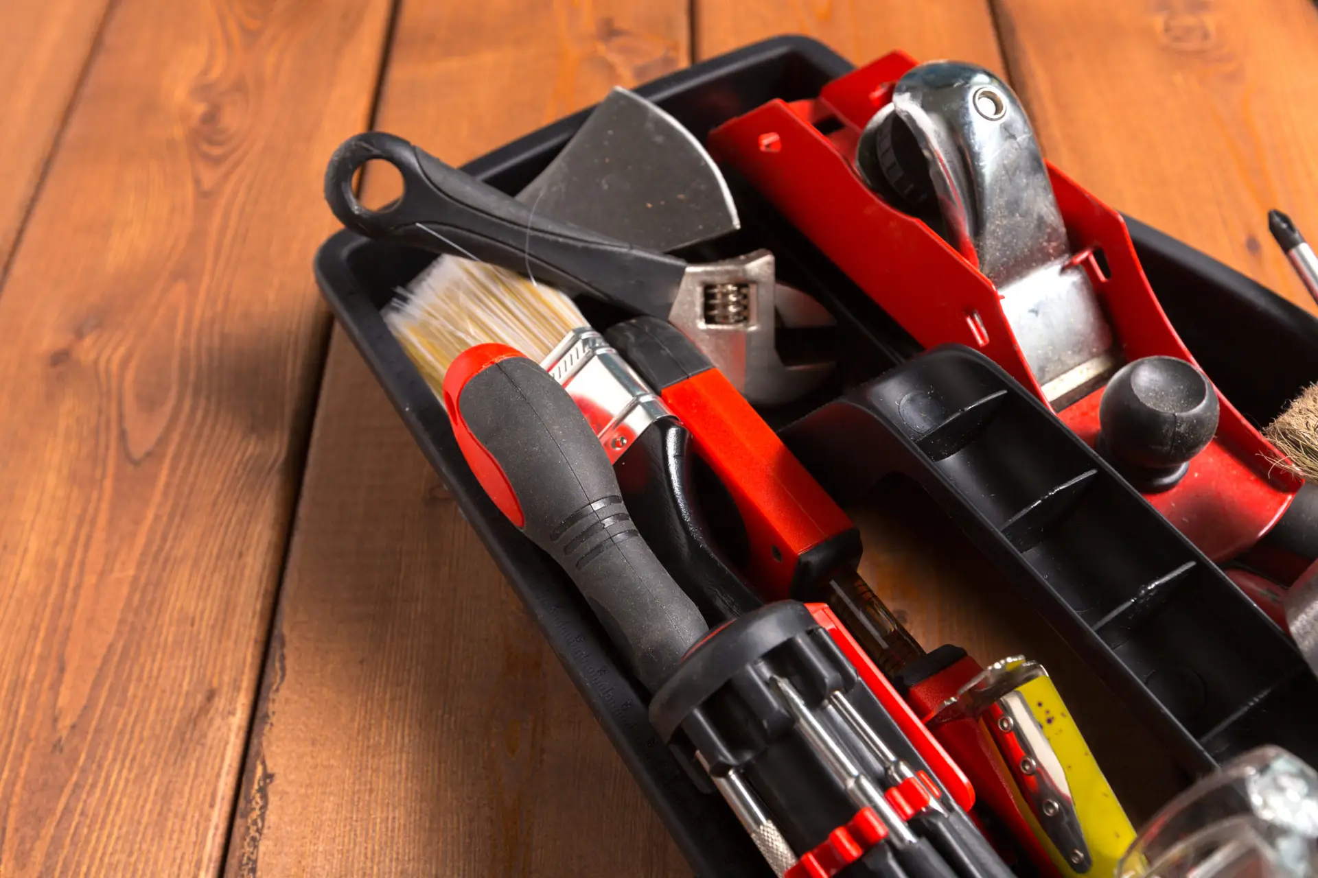 An Urgent Pro handyman provider in Brisbane laying out a professional handyman toolkit including drill, level, spanners and drill bits, with professional equipment visible in a realistic local service setting