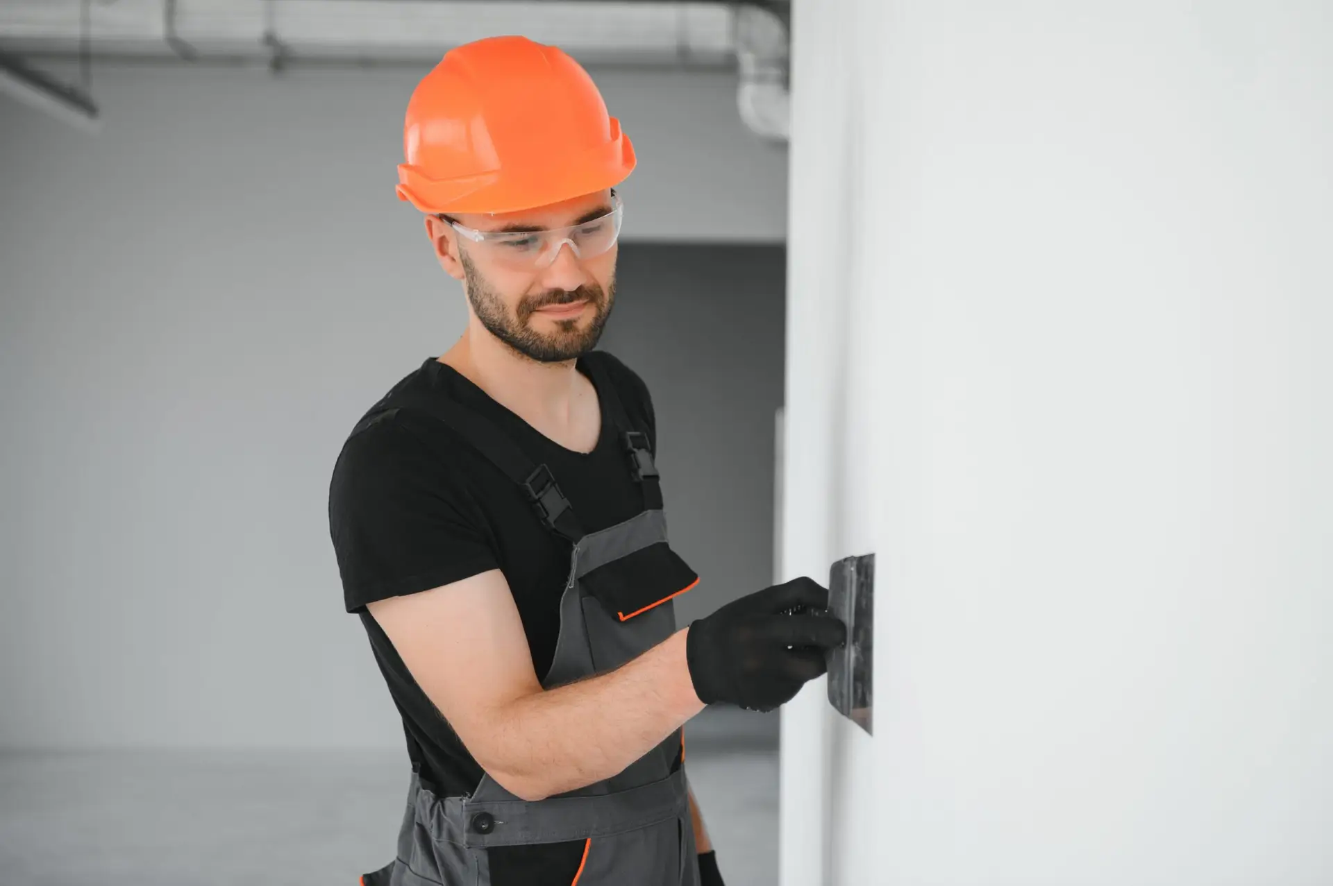 An Urgent Pro handyman provider in Brisbane applying plaster filler to a wall hole, sanding it smooth and priming before repainting, with professional equipment visible in a realistic local service setting