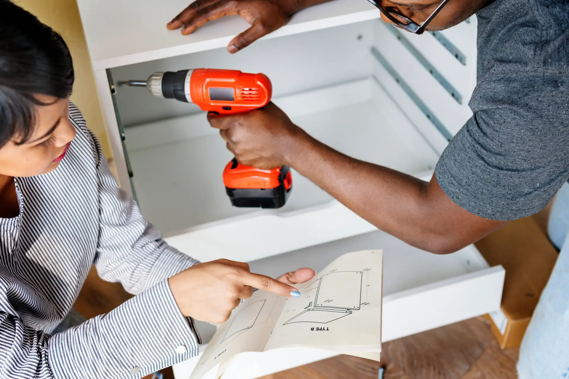An Urgent Pro handyman provider in Gold Coast assembling a flat-pack wardrobe following the instruction sheet with a mallet and Allen key, with professional equipment visible in a realistic local service setting