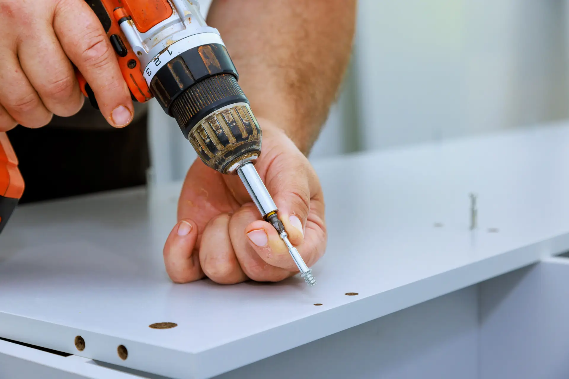 An Urgent Pro handyman provider in Gold Coast measuring, drilling and installing floating wall shelves with a spirit level and wall anchors, with professional equipment visible in a realistic local service setting
