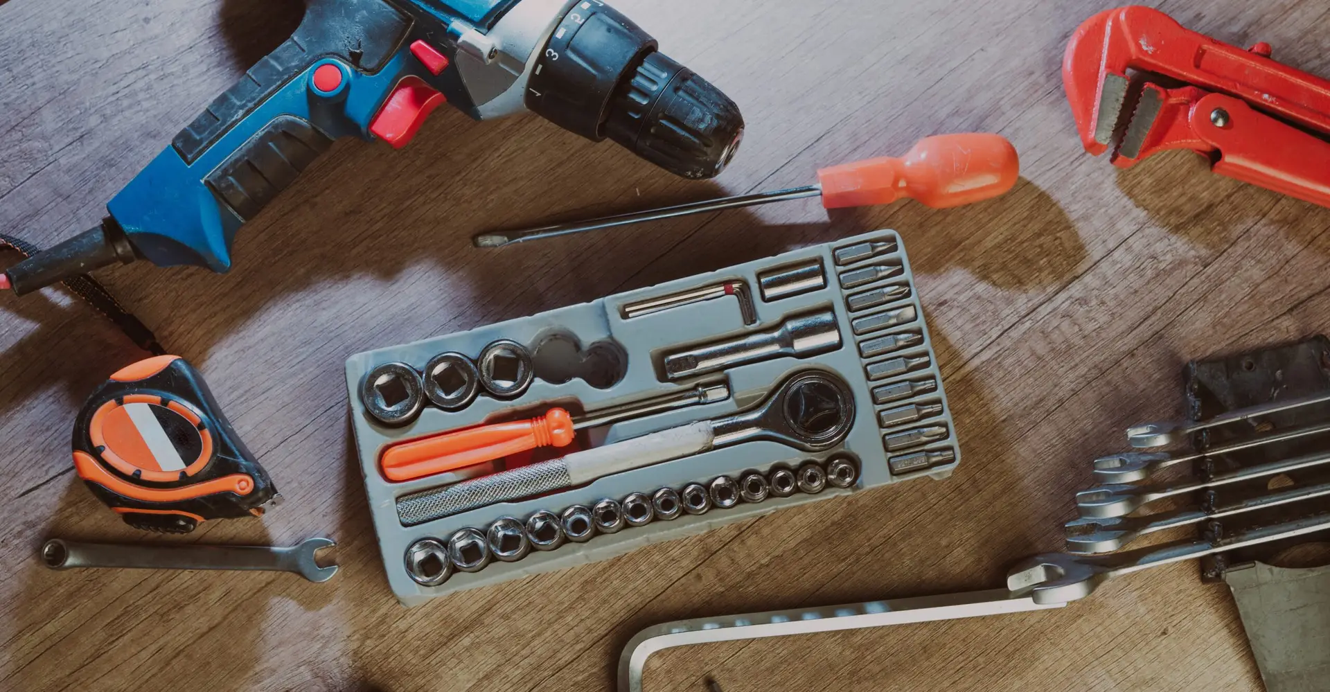 An Urgent Pro handyman provider in Gold Coast laying out a professional handyman toolkit including drill, level, spanners and drill bits, with professional equipment visible in a realistic local service setting