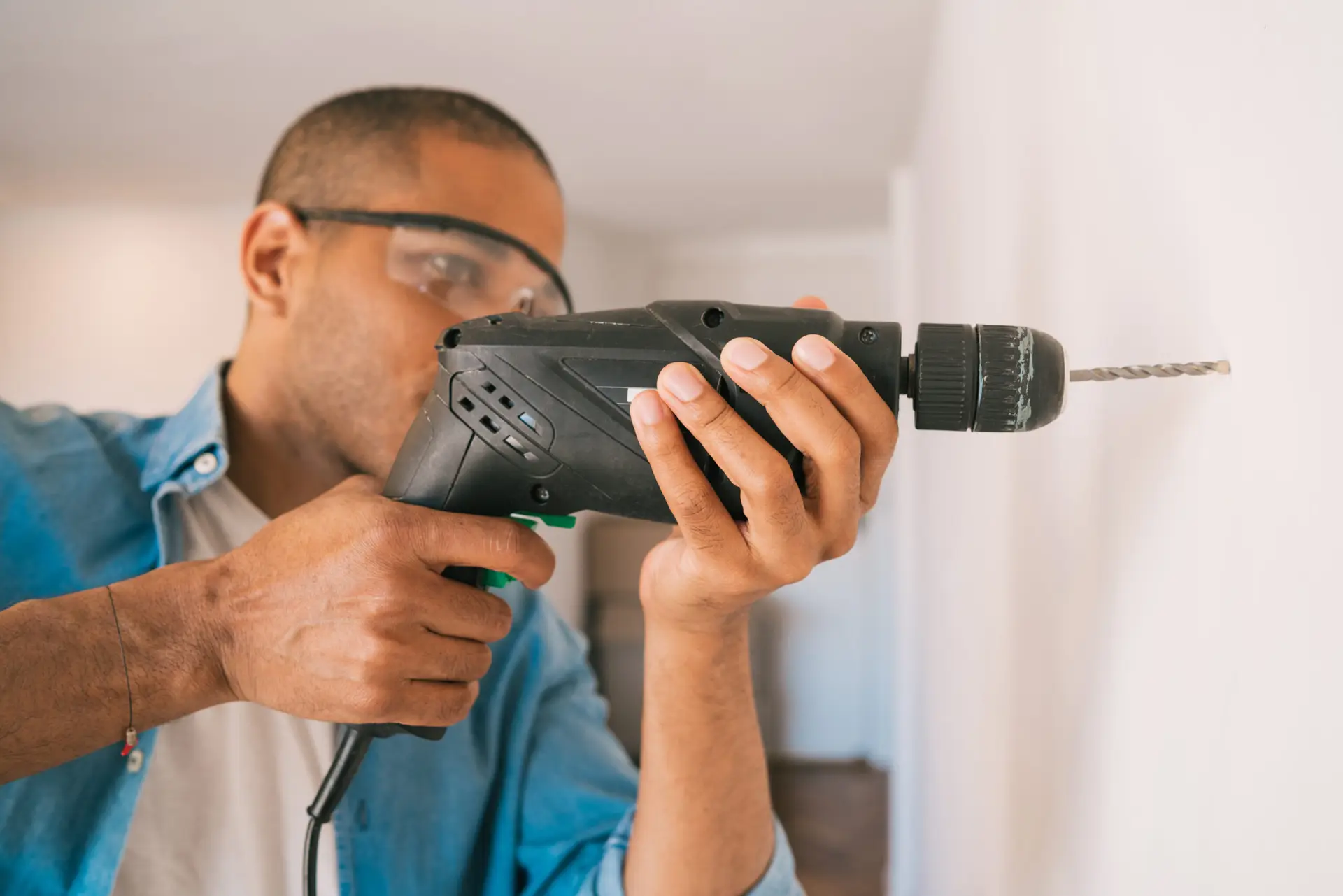 An Urgent Pro handyman provider in Melbourne drilling into a wall to mount a TV bracket using a stud finder and spirit level, with professional equipment visible in a realistic local service setting