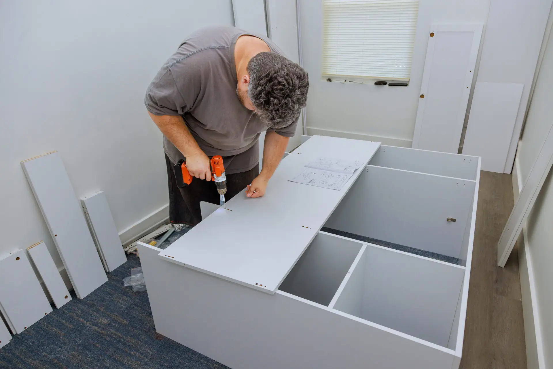An Urgent Pro handyman provider in Melbourne assembling a flat-pack wardrobe following the instruction sheet with a mallet and Allen key, with professional equipment visible in a realistic local service setting