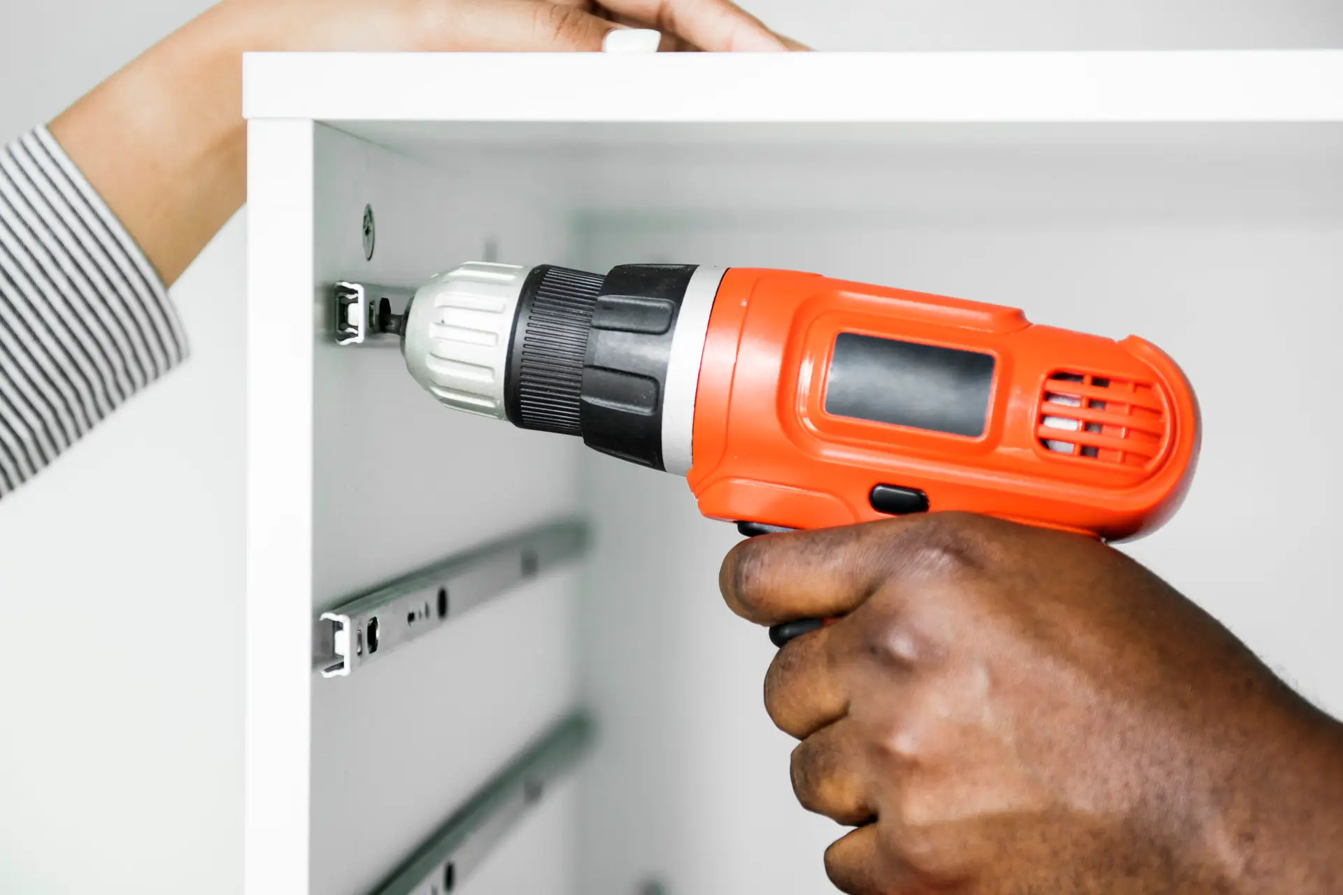 An Urgent Pro handyman provider in Melbourne measuring, drilling and installing floating wall shelves with a spirit level and wall anchors, with professional equipment visible in a realistic local service setting