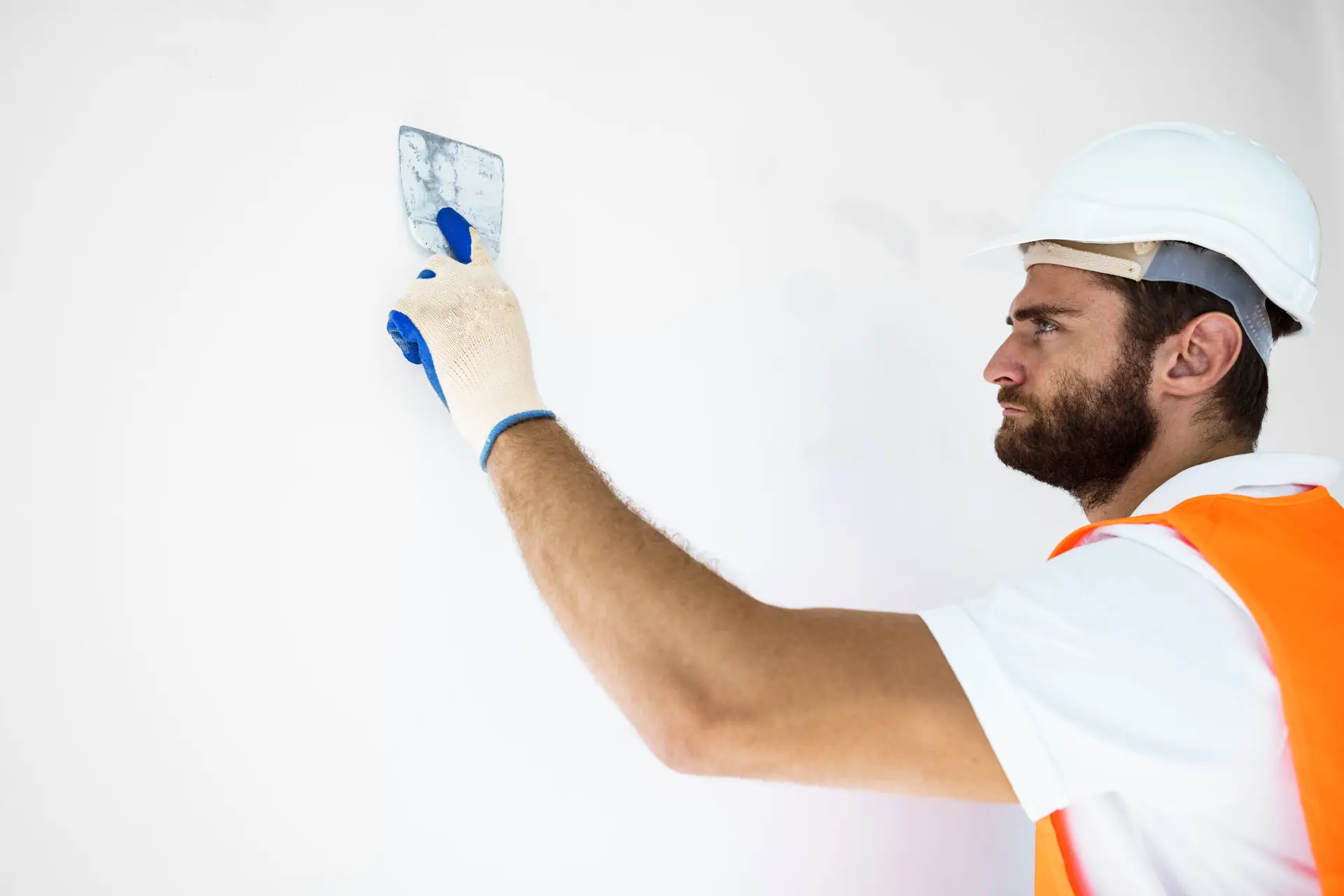 An Urgent Pro handyman provider in Melbourne applying plaster filler to a wall hole, sanding it smooth and priming before repainting, with professional equipment visible in a realistic local service setting