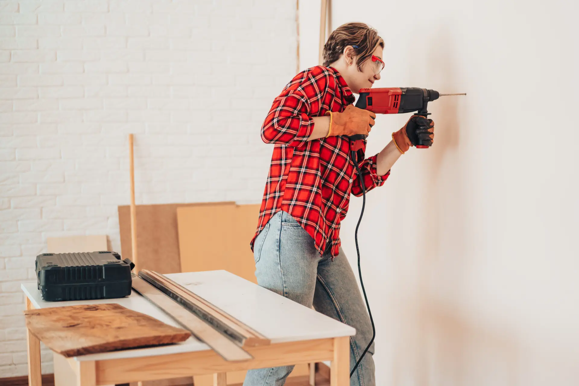 An Urgent Pro handyman provider in Perth drilling into a wall to mount a TV bracket using a stud finder and spirit level, with professional equipment visible in a realistic local service setting