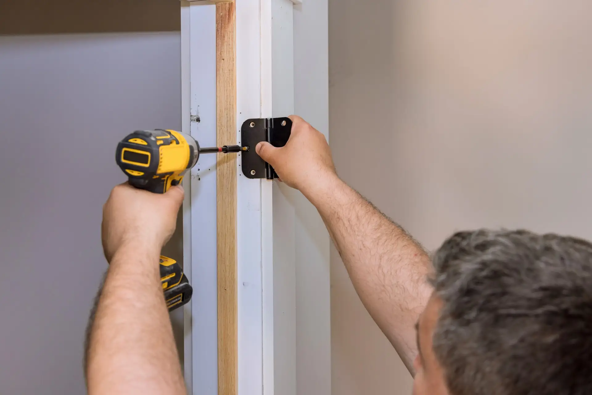 An Urgent Pro handyman provider in Sydney adjusting sticking door hinges and planing a swollen door frame to allow smooth opening, with professional equipment visible in a realistic local service setting