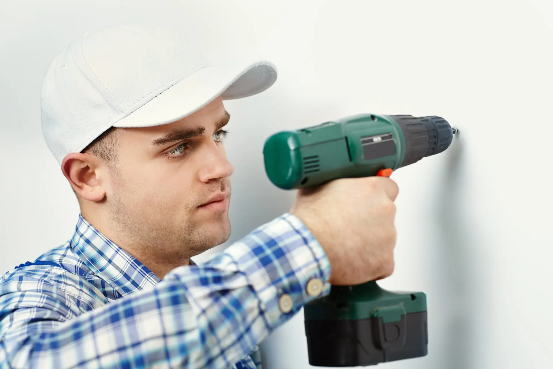 An Urgent Pro handyman provider in Sydney drilling into a wall to mount a TV bracket using a stud finder and spirit level, with professional equipment visible in a realistic local service setting