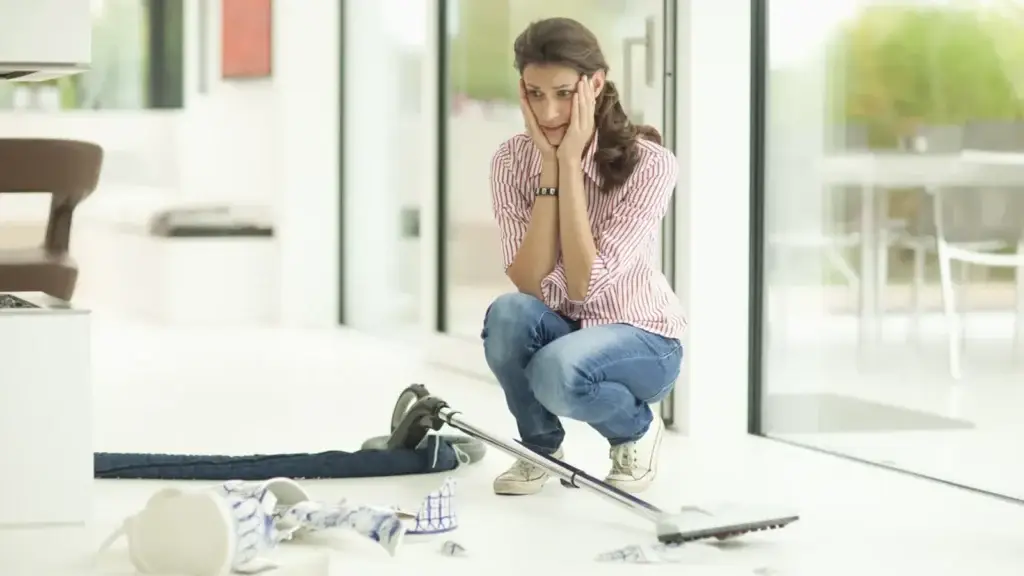 Frustrated homeowner crouching over broken ceramic items on the floor after a professional house clean in Australia