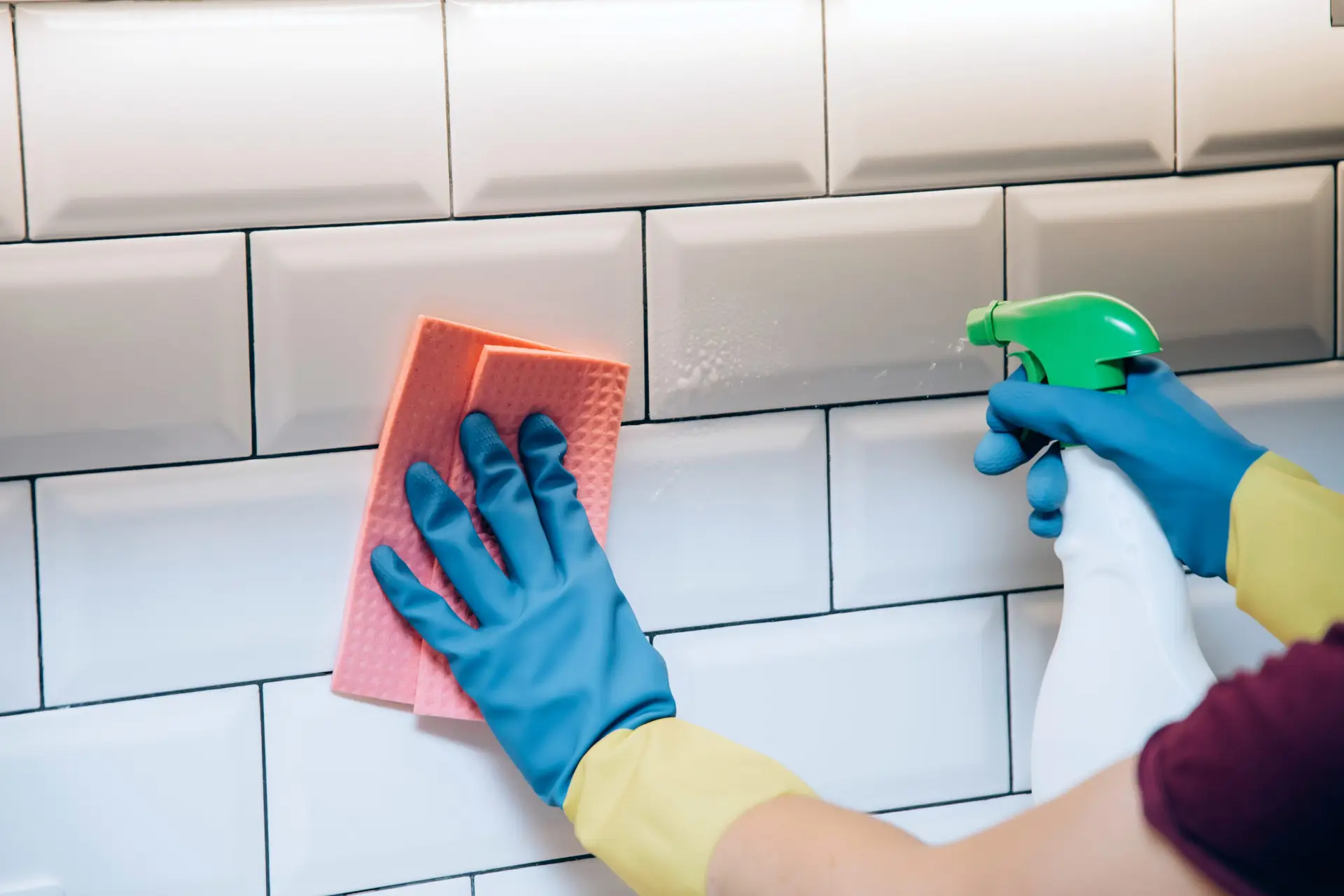 An Urgent Pro house cleaning provider in Brisbane scrubbing shower tiles, polishing the vanity mirror and cleaning the toilet in a Brisbane home bathroom, with professional equipment visible in a realistic local service setting