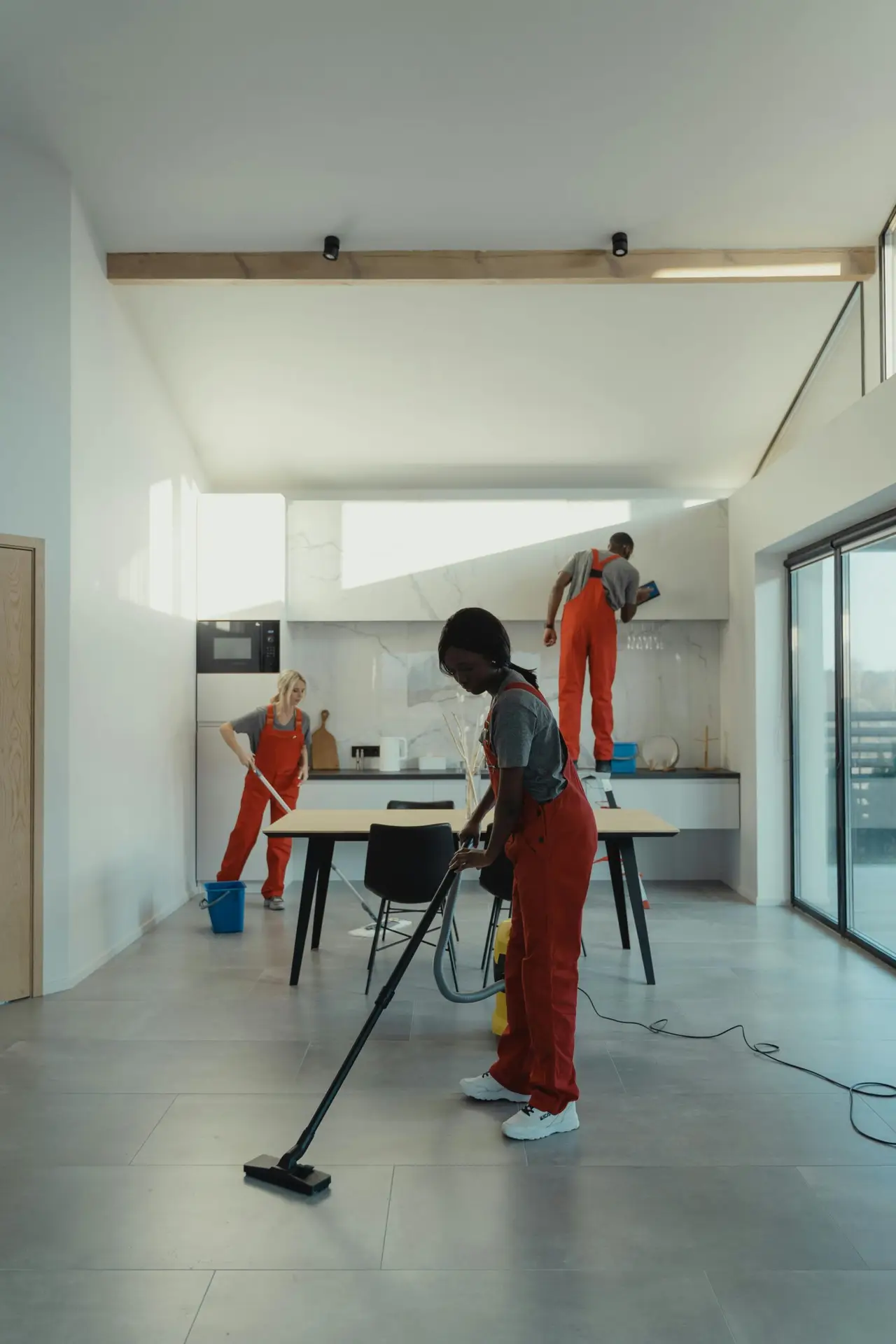 An Urgent Pro house cleaning provider in Brisbane scrubbing the sink, wiping the stovetop and cleaning behind the taps in a Brisbane family kitchen, with professional equipment visible in a realistic local service setting