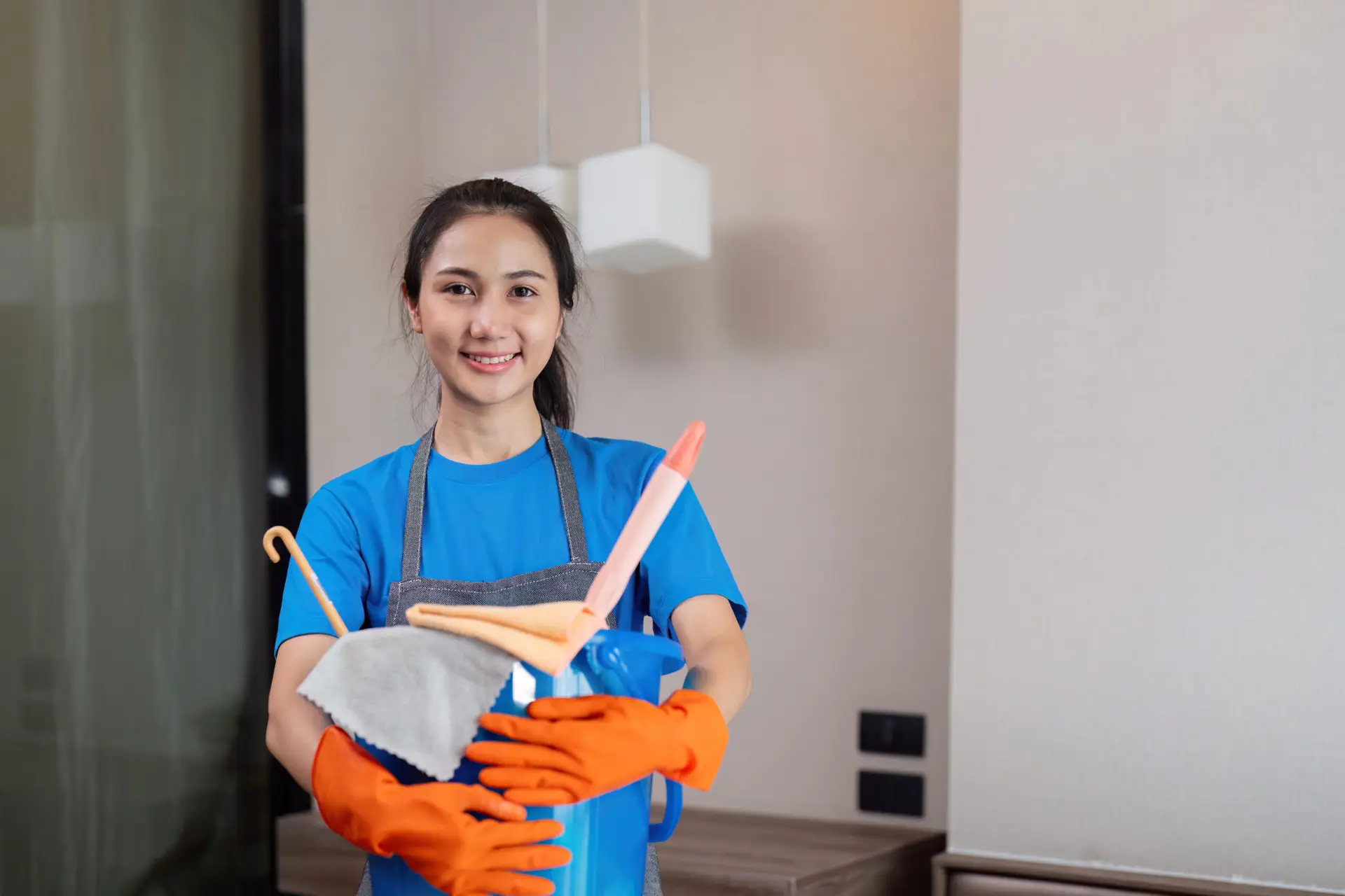 An Urgent Pro house cleaning provider in Gold Coast wiping kitchen benches, appliance fronts and cupboard doors in an occupied Gold Coast family home, with professional equipment visible in a realistic local service setting