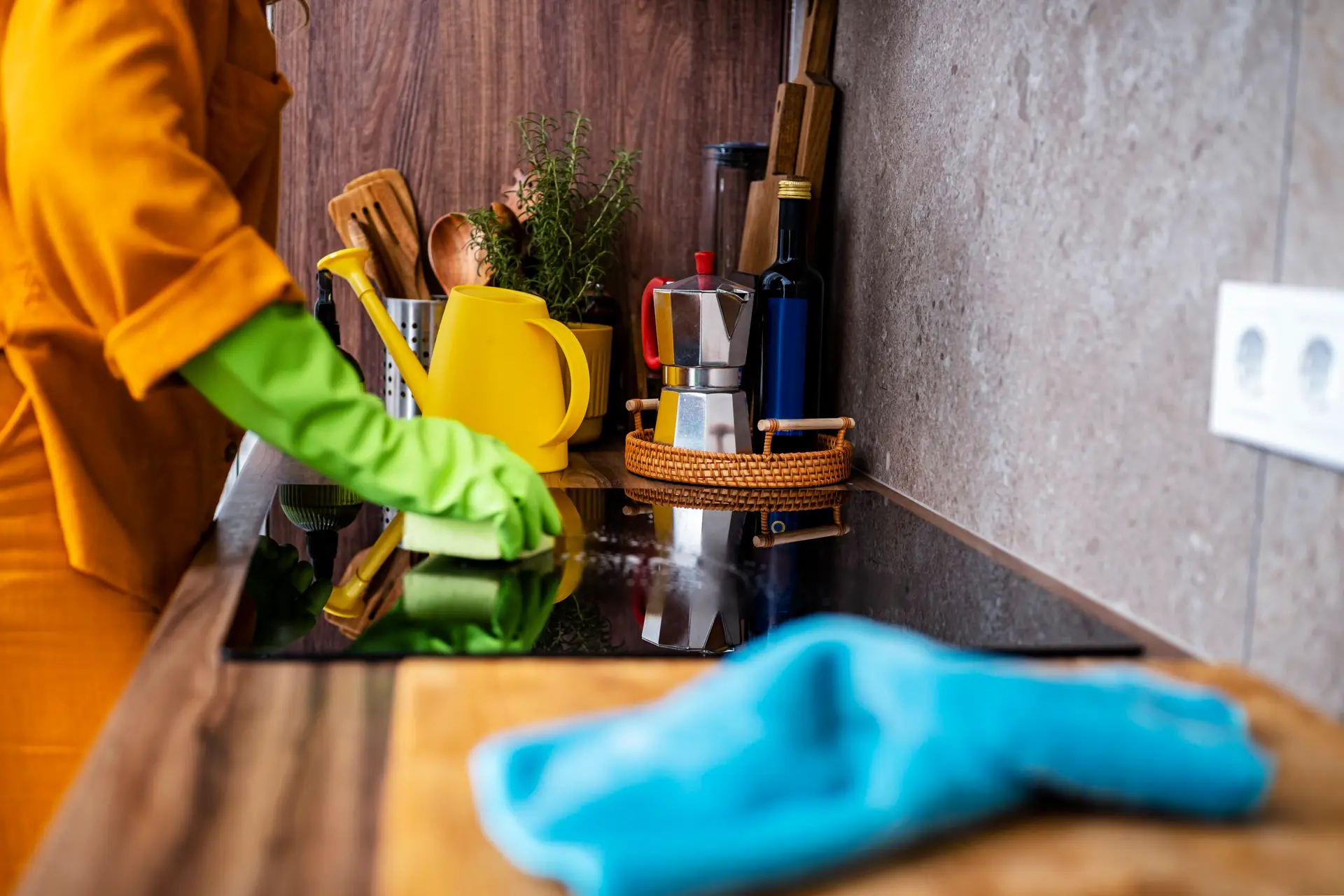 An Urgent Pro house cleaning provider in Melbourne wiping kitchen benches, appliance fronts and cupboard doors in an occupied Melbourne family home, with professional equipment visible in a realistic local service setting