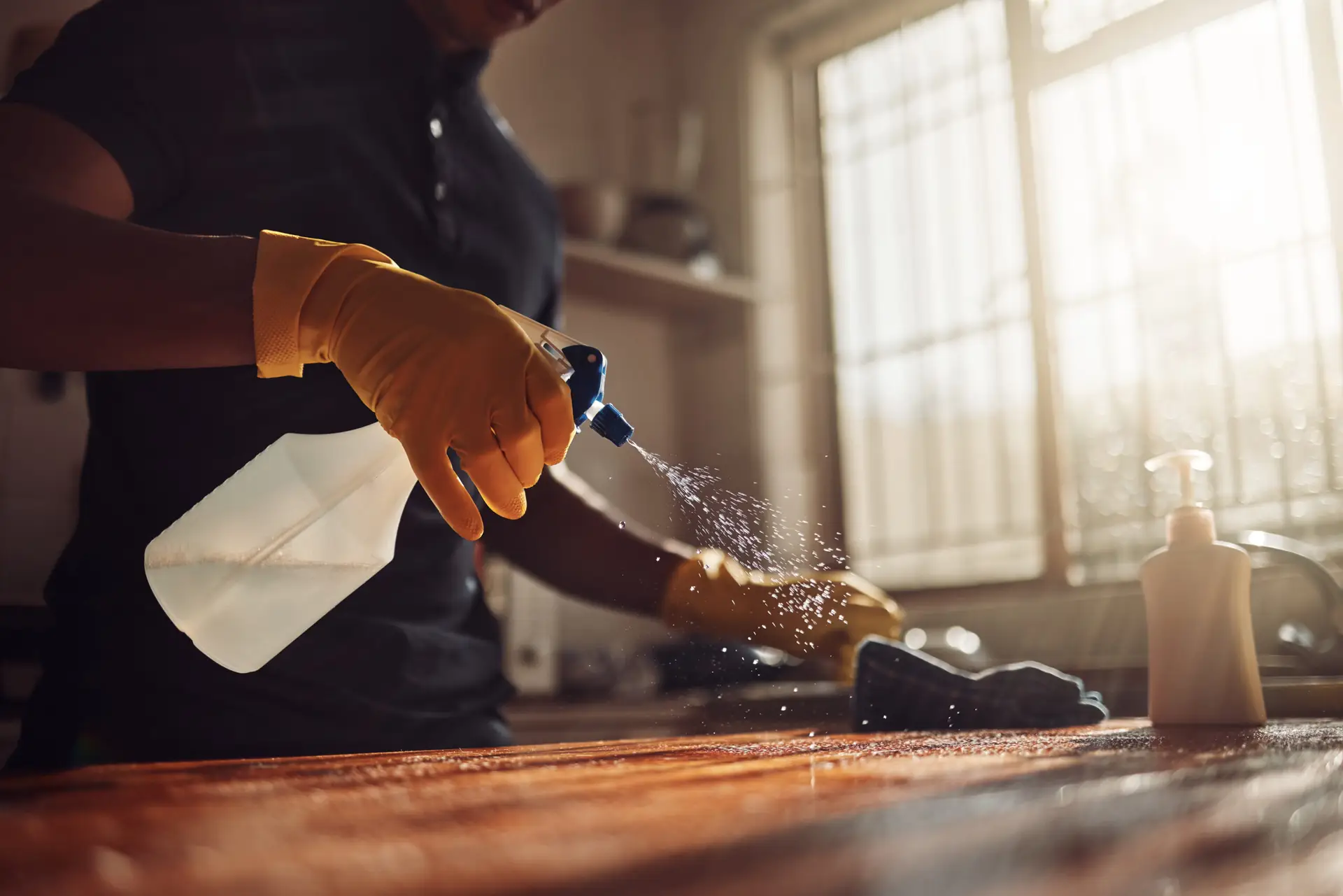 An Urgent Pro house cleaning provider in Perth scrubbing the sink, wiping the stovetop and cleaning behind the taps in a Perth family kitchen, with professional equipment visible in a realistic local service setting