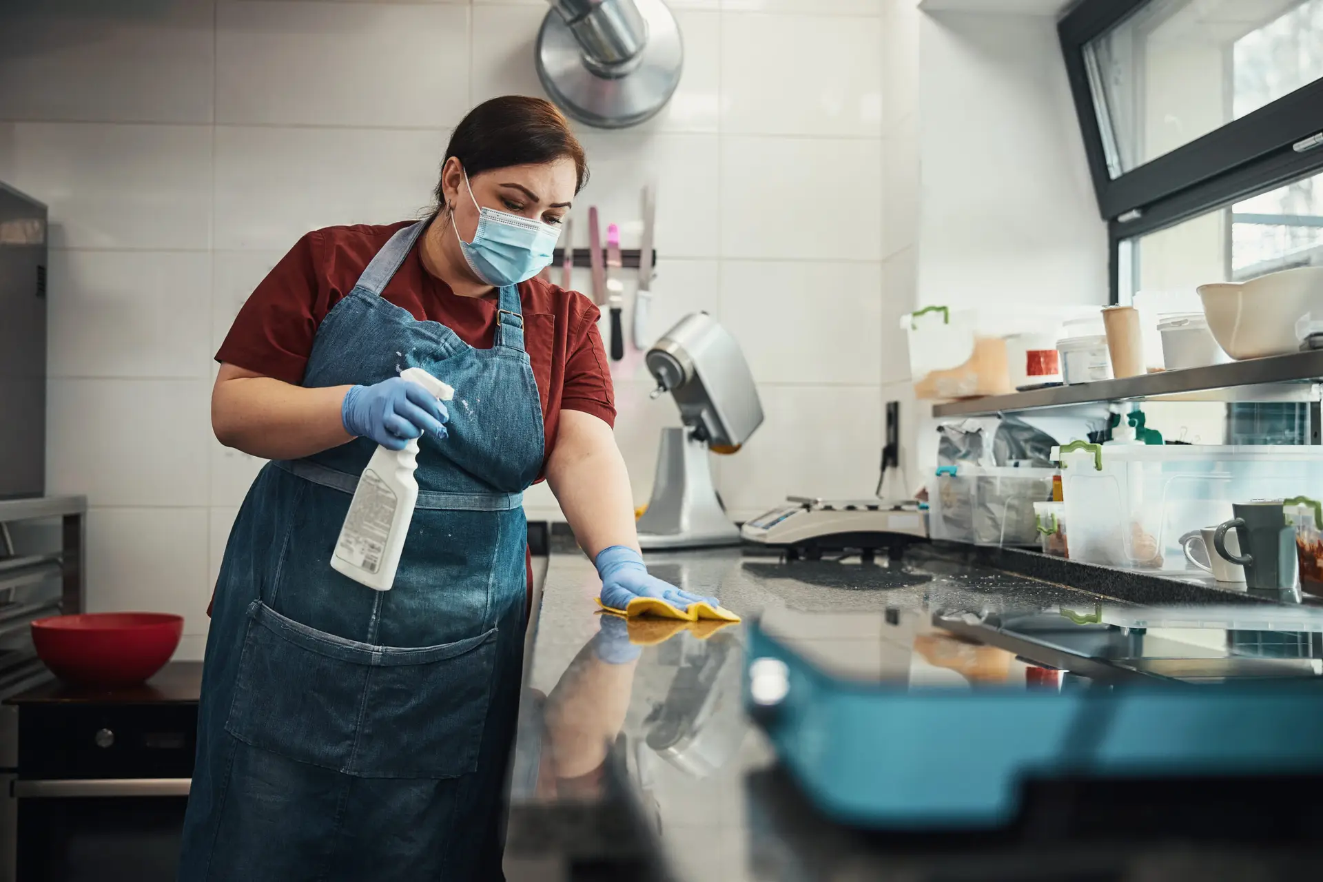 An Urgent Pro house cleaning provider in Sydney scrubbing the sink, wiping the stovetop and cleaning behind the taps in a Sydney family kitchen, with professional equipment visible in a realistic local service setting