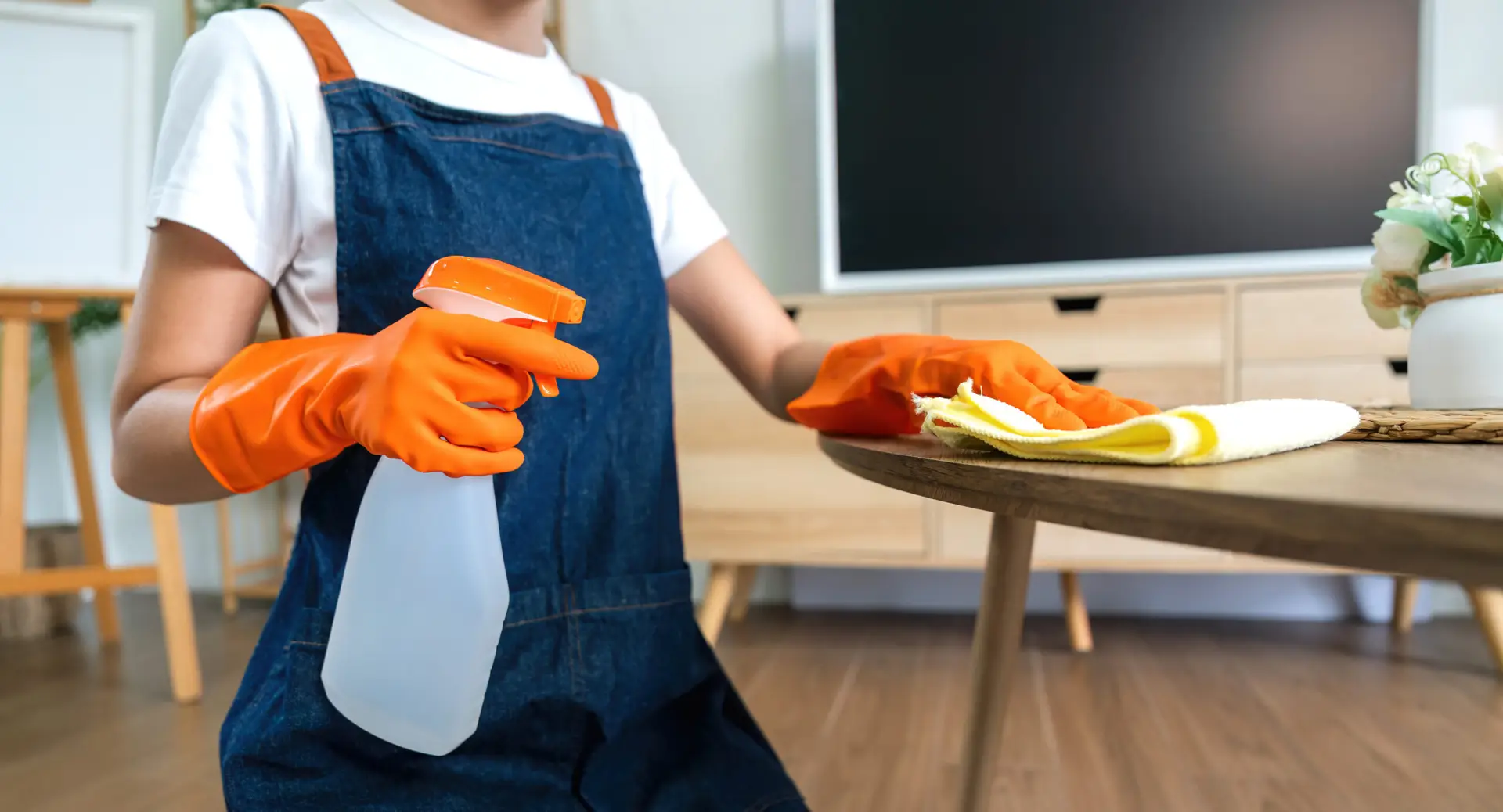 An Urgent Pro house cleaning provider in Sydney vacuuming the sofa, dusting shelves and wiping the coffee table in a Sydney family living room, with professional equipment visible in a realistic local service setting