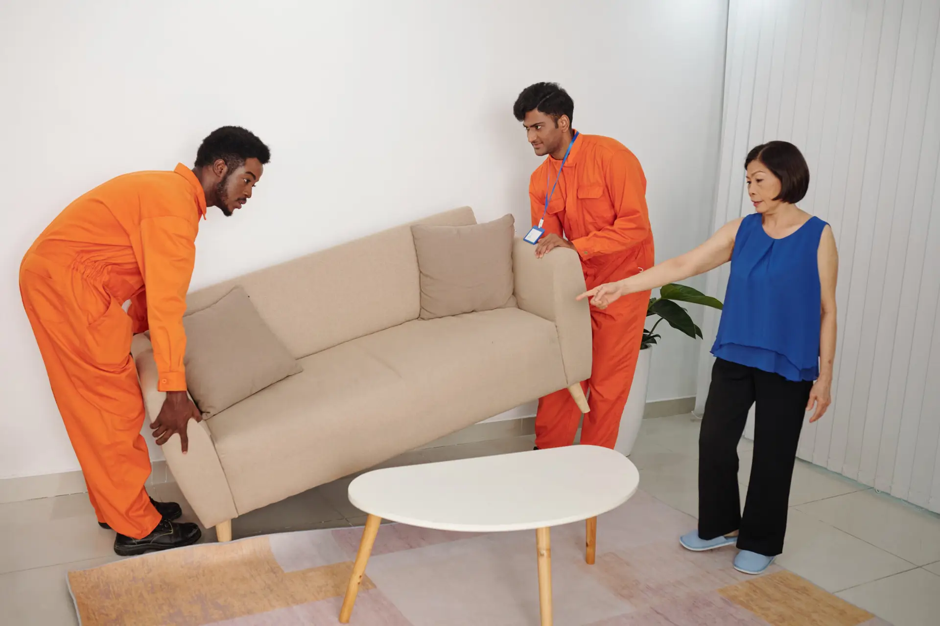 An Urgent Pro house removalists provider in Brisbane carrying a wrapped sofa out the front door of a home to the waiting removal truck, with professional equipment visible in a realistic local service setting