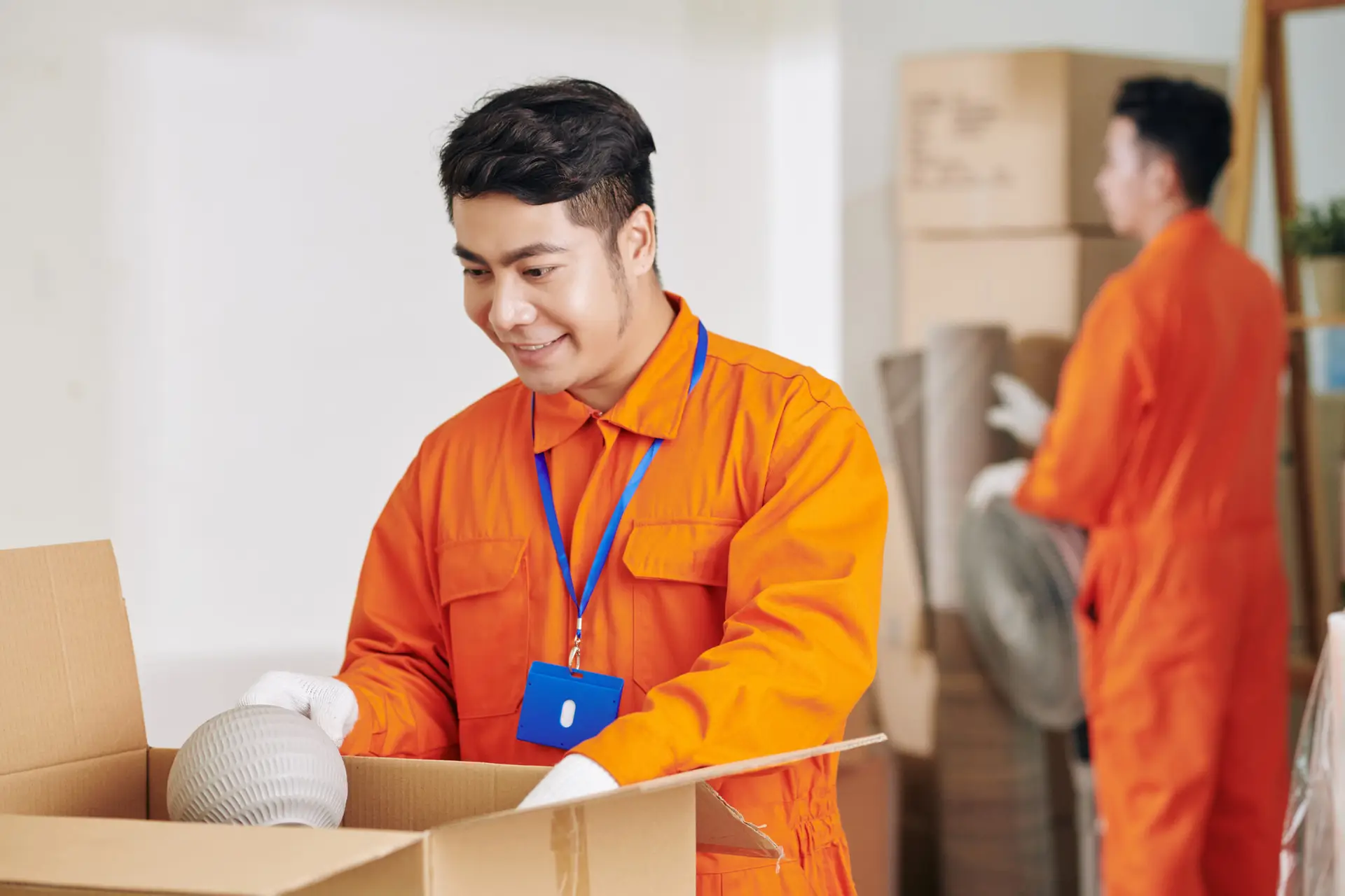 An Urgent Pro house removalists provider in Gold Coast stacking and labelling cardboard moving boxes in a room ready for efficient loading, with professional equipment visible in a realistic local service setting