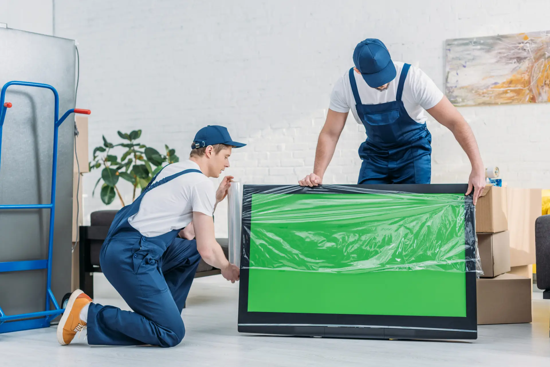 An Urgent Pro house removalists provider in Gold Coast carefully loading fragile glass-front furniture with padding into the removal truck, with professional equipment visible in a realistic local service setting