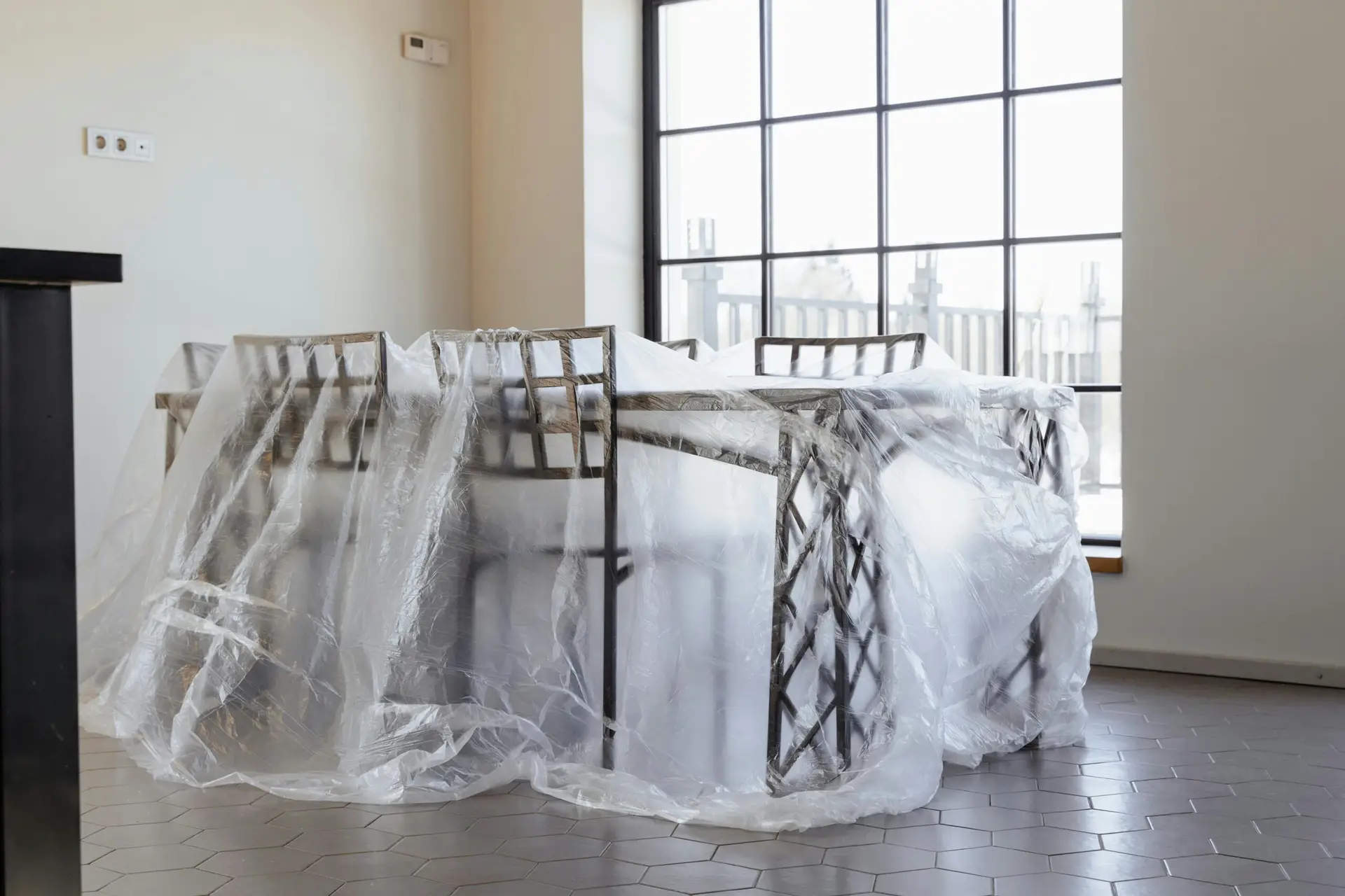 An Urgent Pro house removalists provider in Gold Coast wrapping a tall wardrobe in moving blankets and plastic stretch wrap before loading, with professional equipment visible in a realistic local service setting