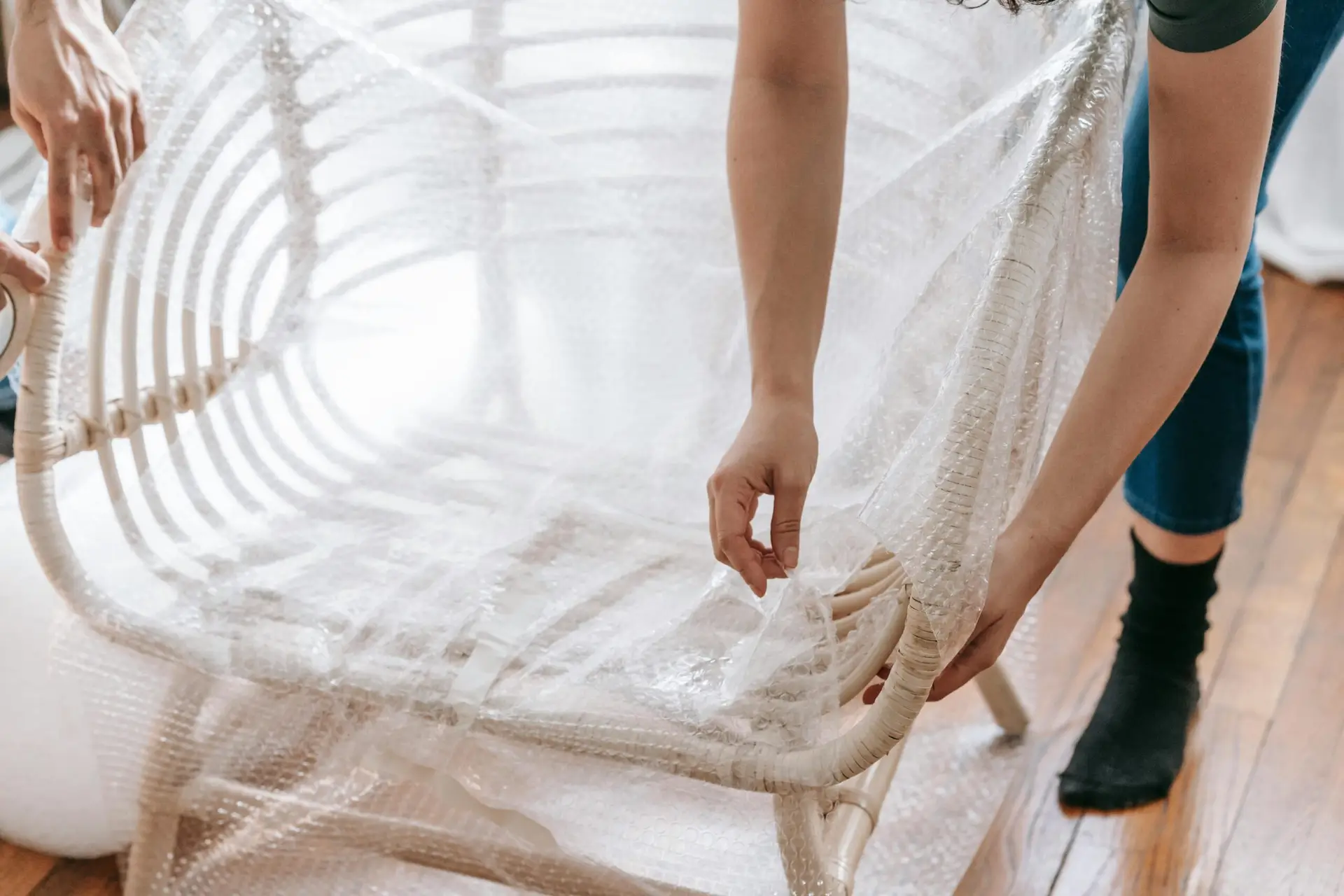 An Urgent Pro house removalists provider in Melbourne wrapping a tall wardrobe in moving blankets and plastic stretch wrap before loading, with professional equipment visible in a realistic local service setting