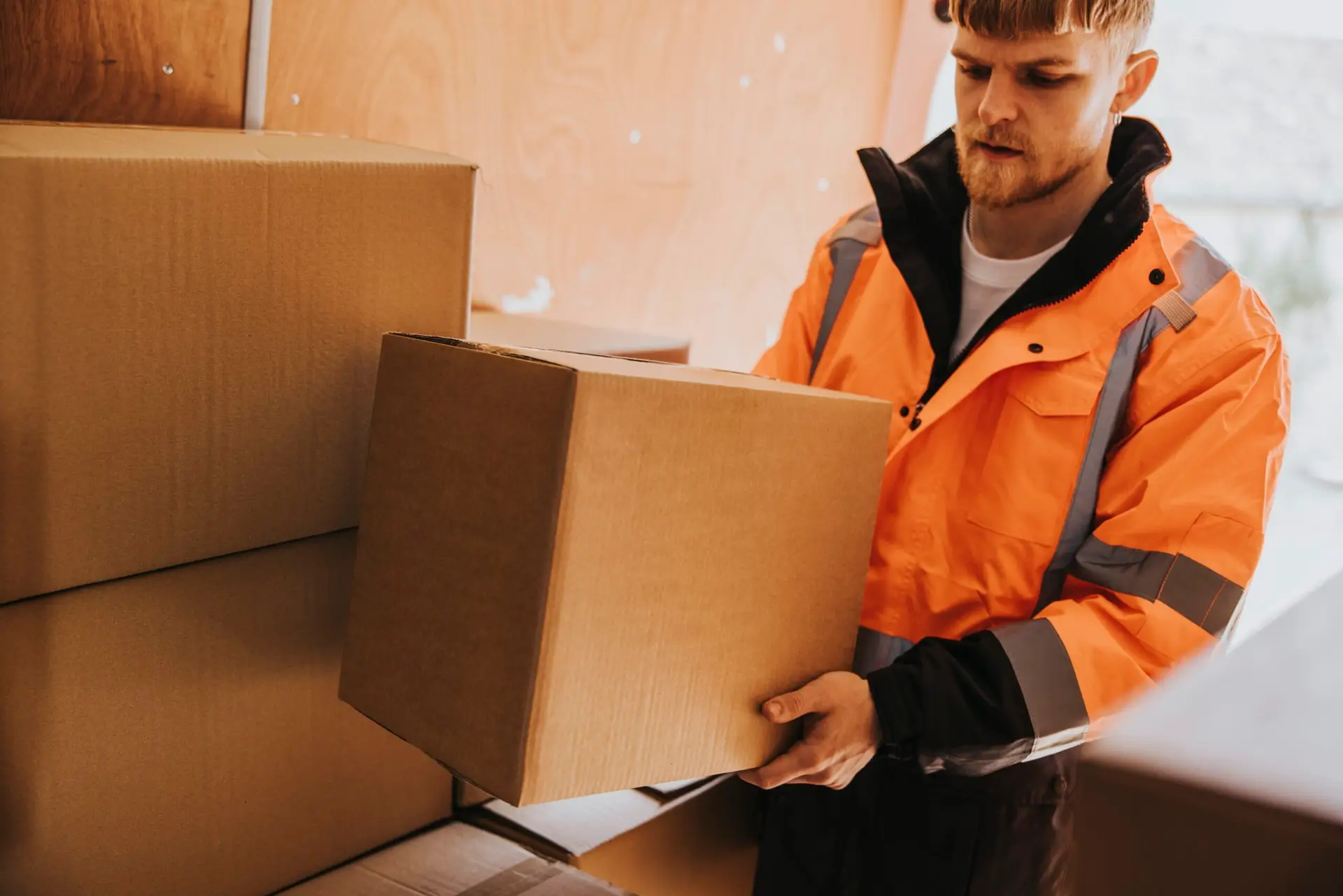 An Urgent Pro house removalists provider in Perth stacking and labelling cardboard moving boxes in a room ready for efficient loading, with professional equipment visible in a realistic local service setting
