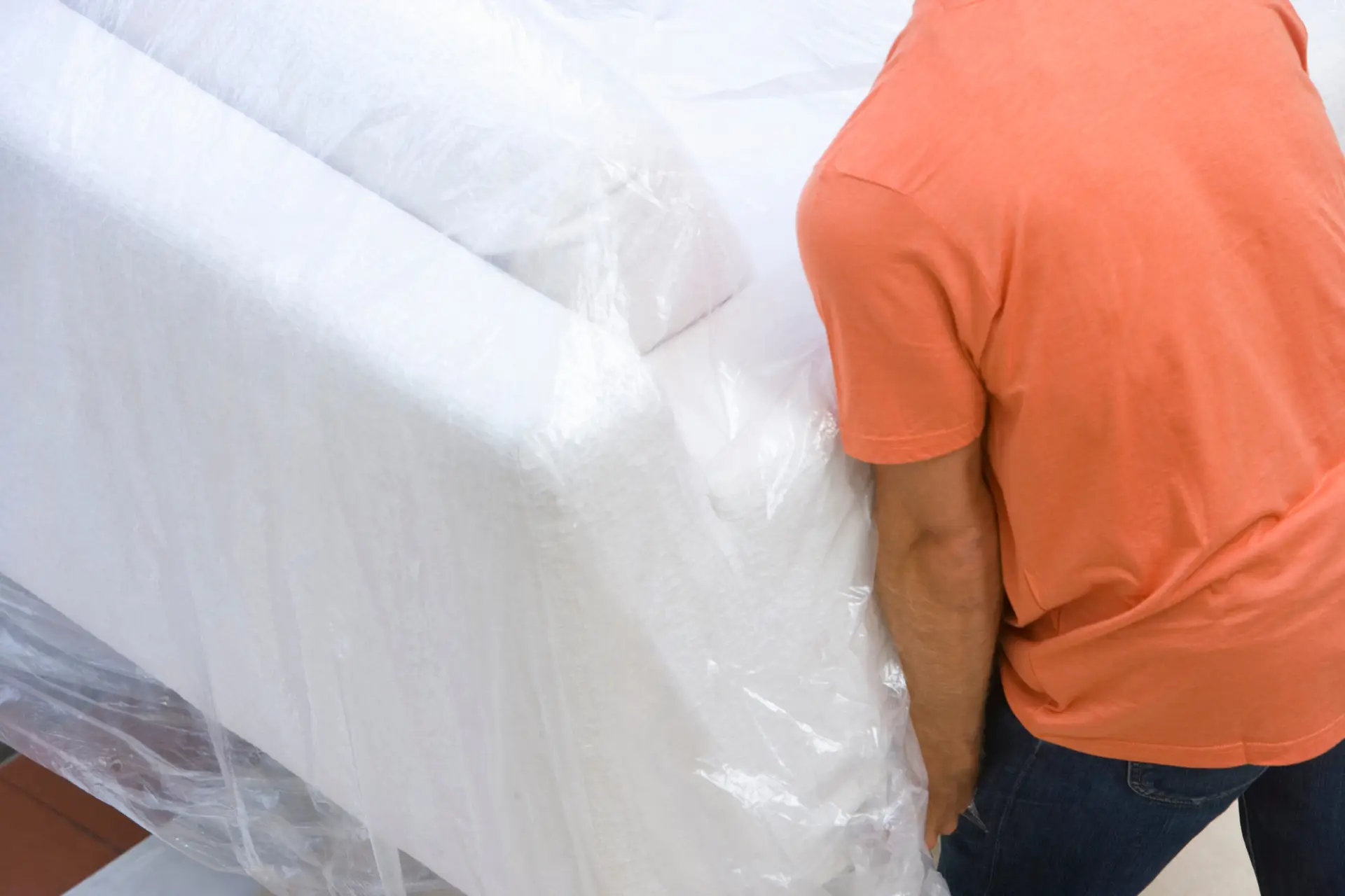 An Urgent Pro house removalists provider in Sydney wrapping a tall wardrobe in moving blankets and plastic stretch wrap before loading, with professional equipment visible in a realistic local service setting