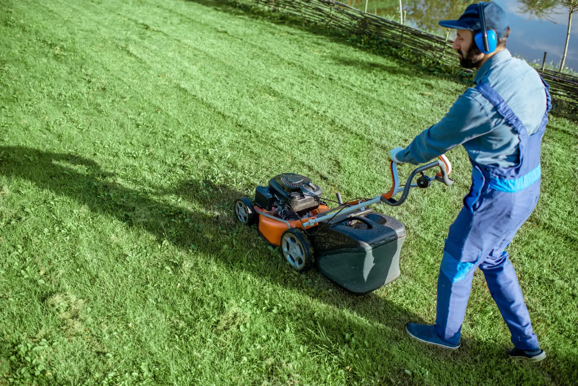 An Urgent Pro lawn mowing provider in Brisbane operating a professional petrol mower across a residential backyard leaving clean mowing rows, with professional equipment visible in a realistic local service setting