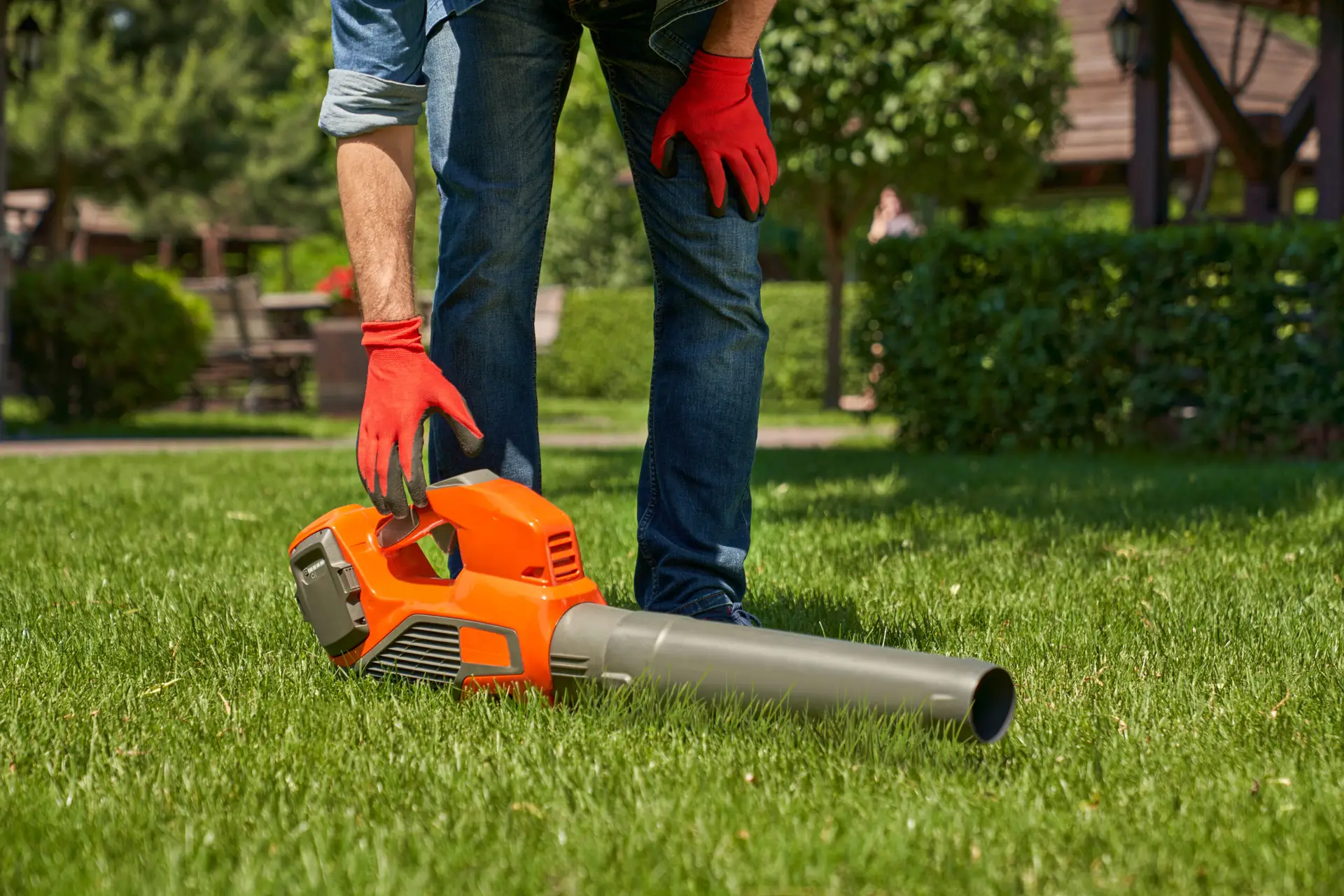 An Urgent Pro lawn mowing provider in Gold Coast using a leaf blower to clear grass clippings from the path and driveway after mowing, with professional equipment visible in a realistic local service setting