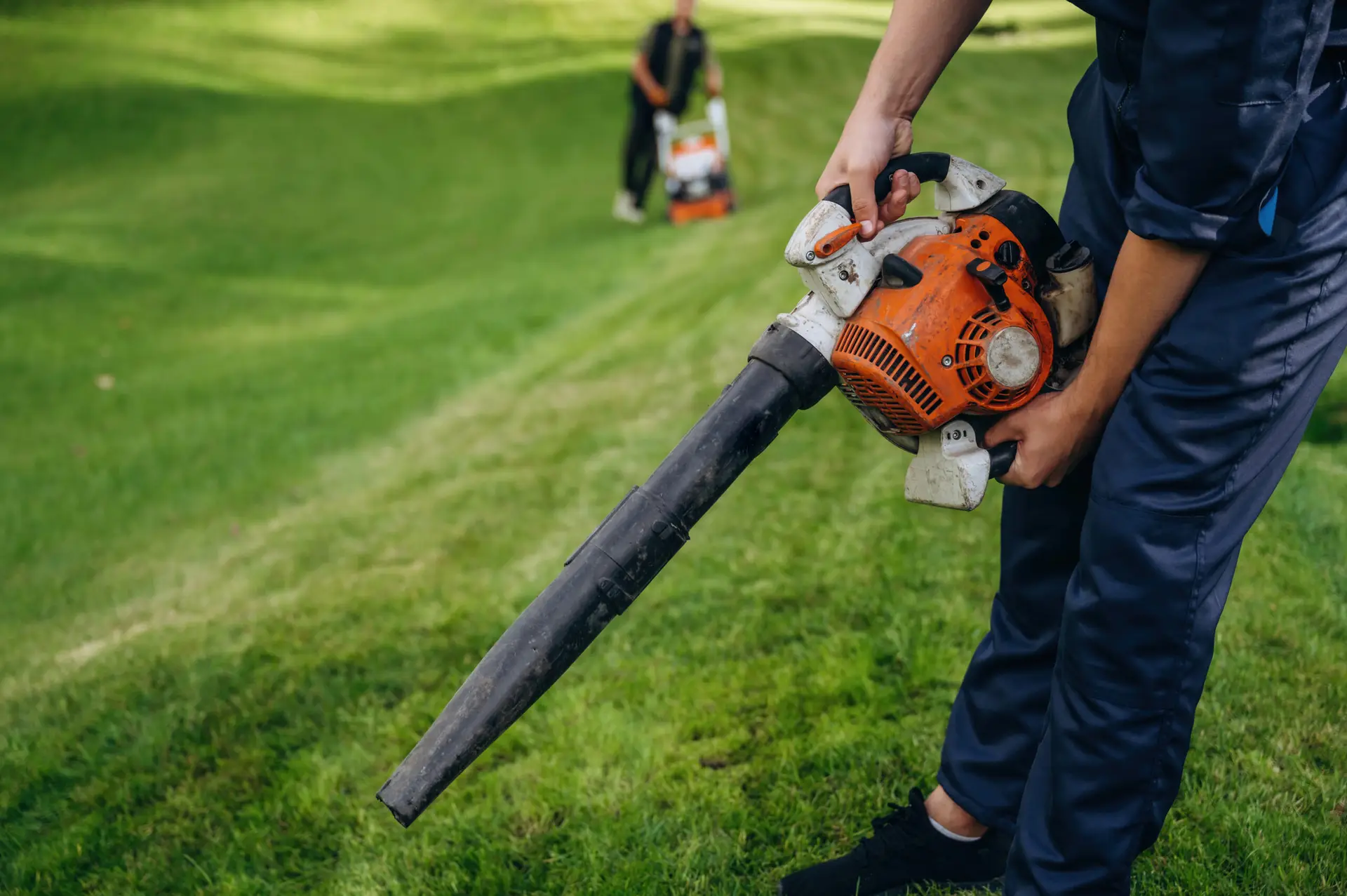 An Urgent Pro lawn mowing provider in Melbourne laying out professional mowing equipment including mower, trimmer, blower and shears before the job, with professional equipment visible in a realistic local service setting