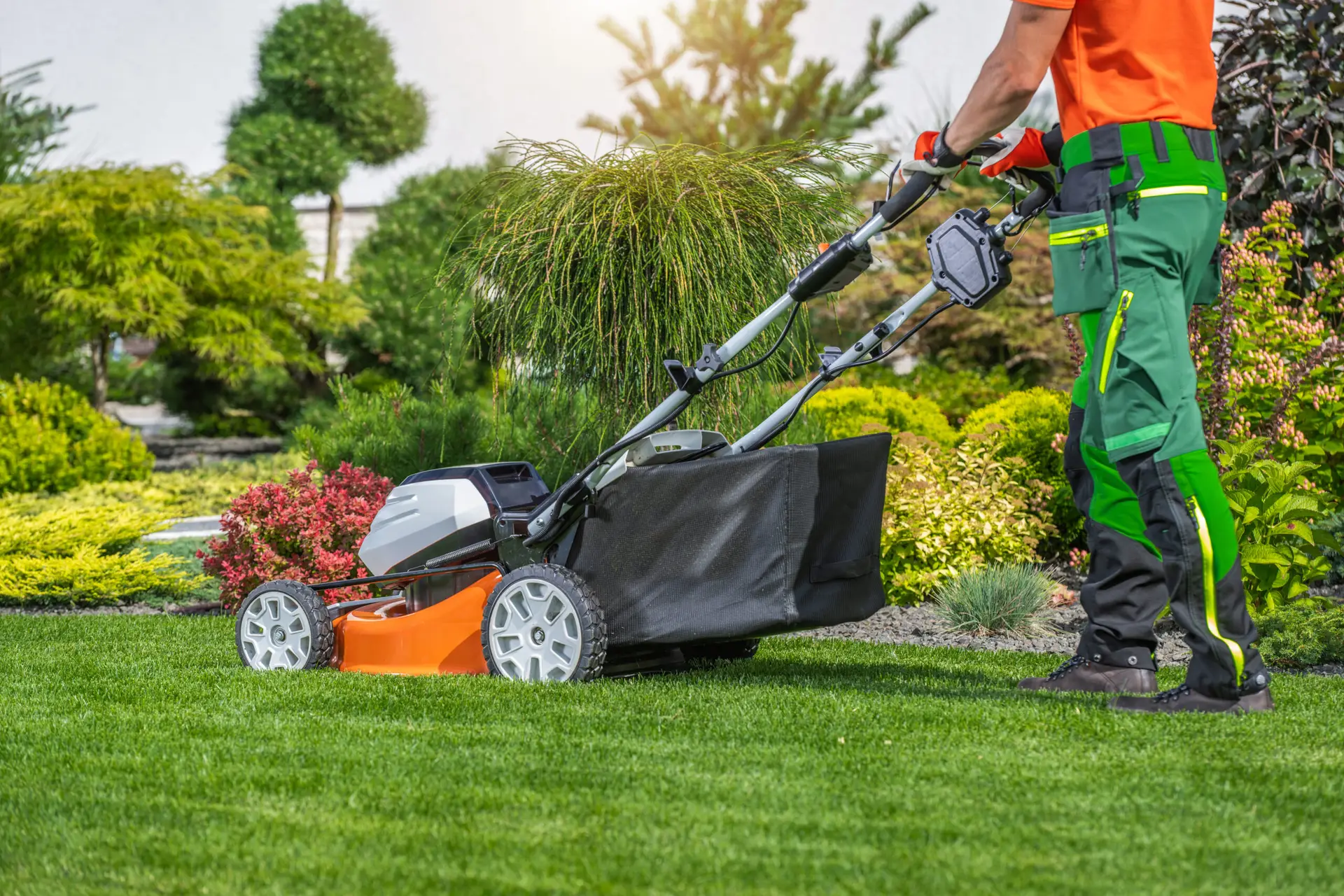 An Urgent Pro lawn mowing provider in Perth mowing the front lawn of a residential property with a push mower beside the footpath, with professional equipment visible in a realistic local service setting