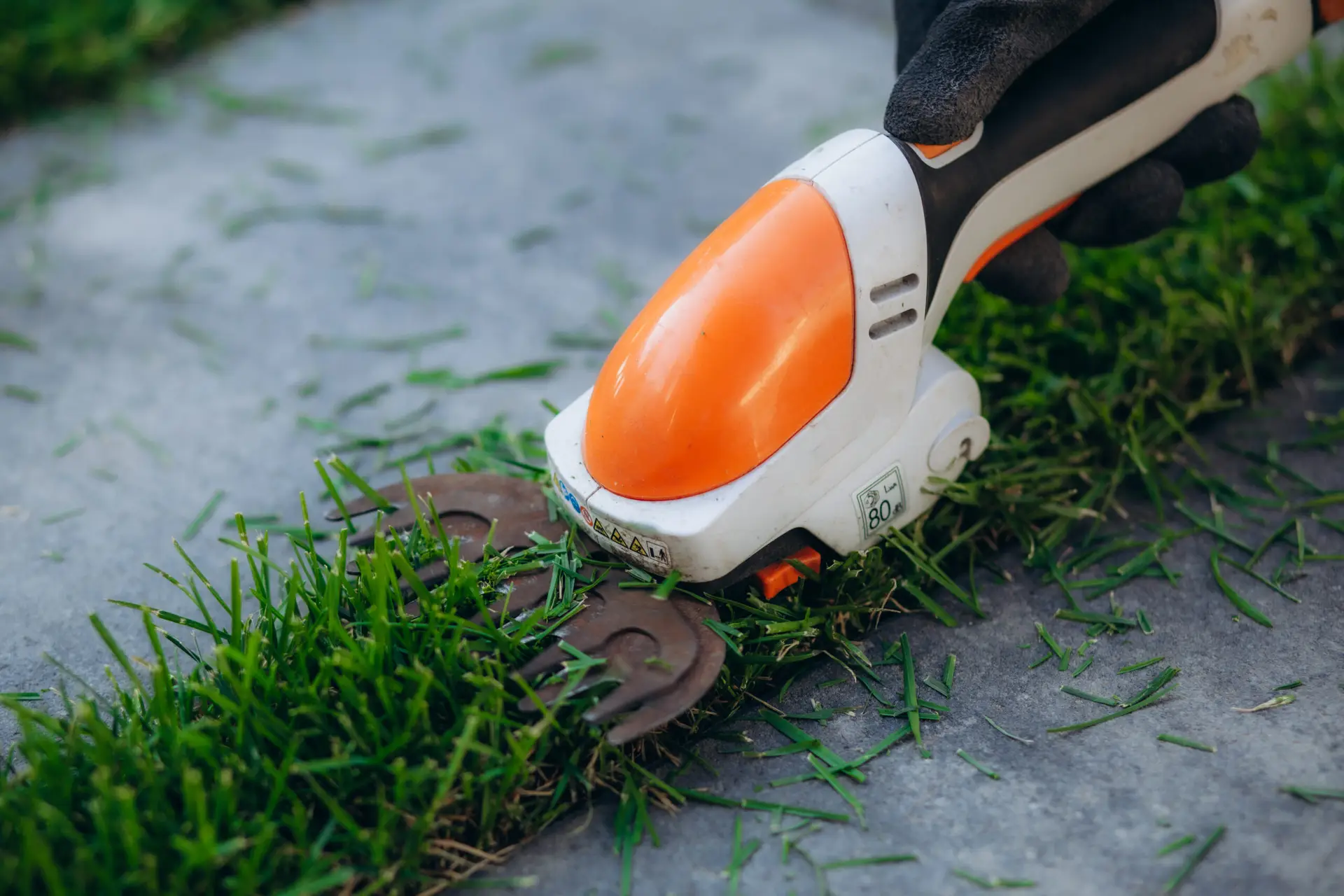 An Urgent Pro lawn mowing provider in Perth laying out professional mowing equipment including mower, trimmer, blower and shears before the job, with professional equipment visible in a realistic local service setting
