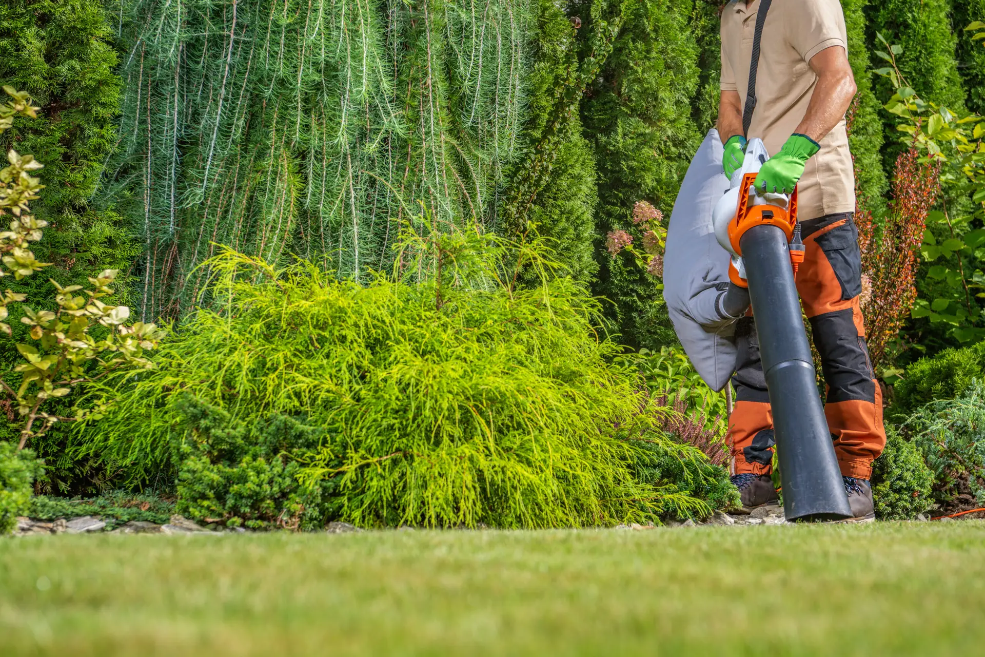 An Urgent Pro lawn mowing provider in Sydney using a leaf blower to clear grass clippings from the path and driveway after mowing, with professional equipment visible in a realistic local service setting